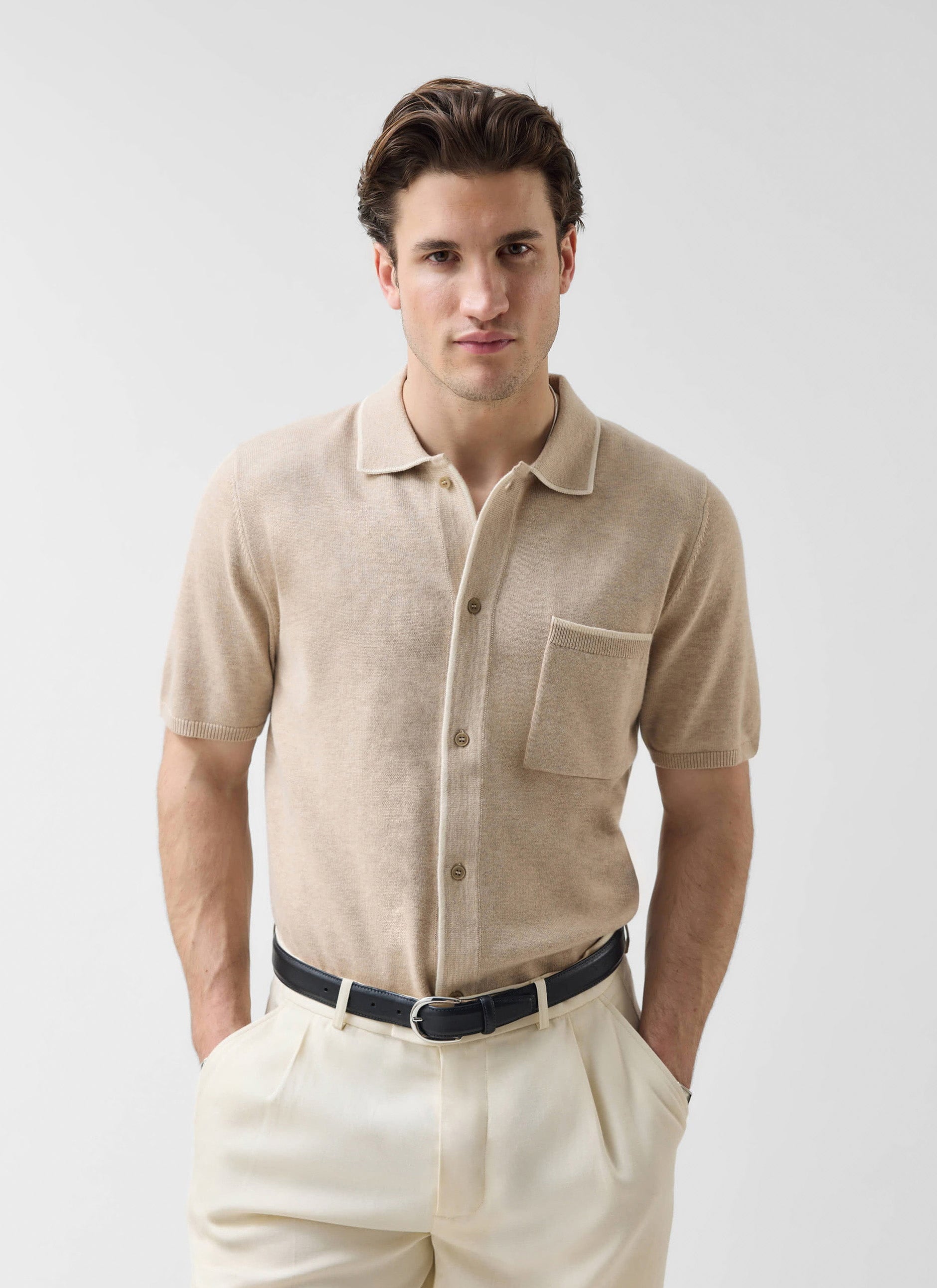 A male model wears the Percival Contrast Trim Regular Knitted Shirt in beige, styled with cream trousers and a black belt.