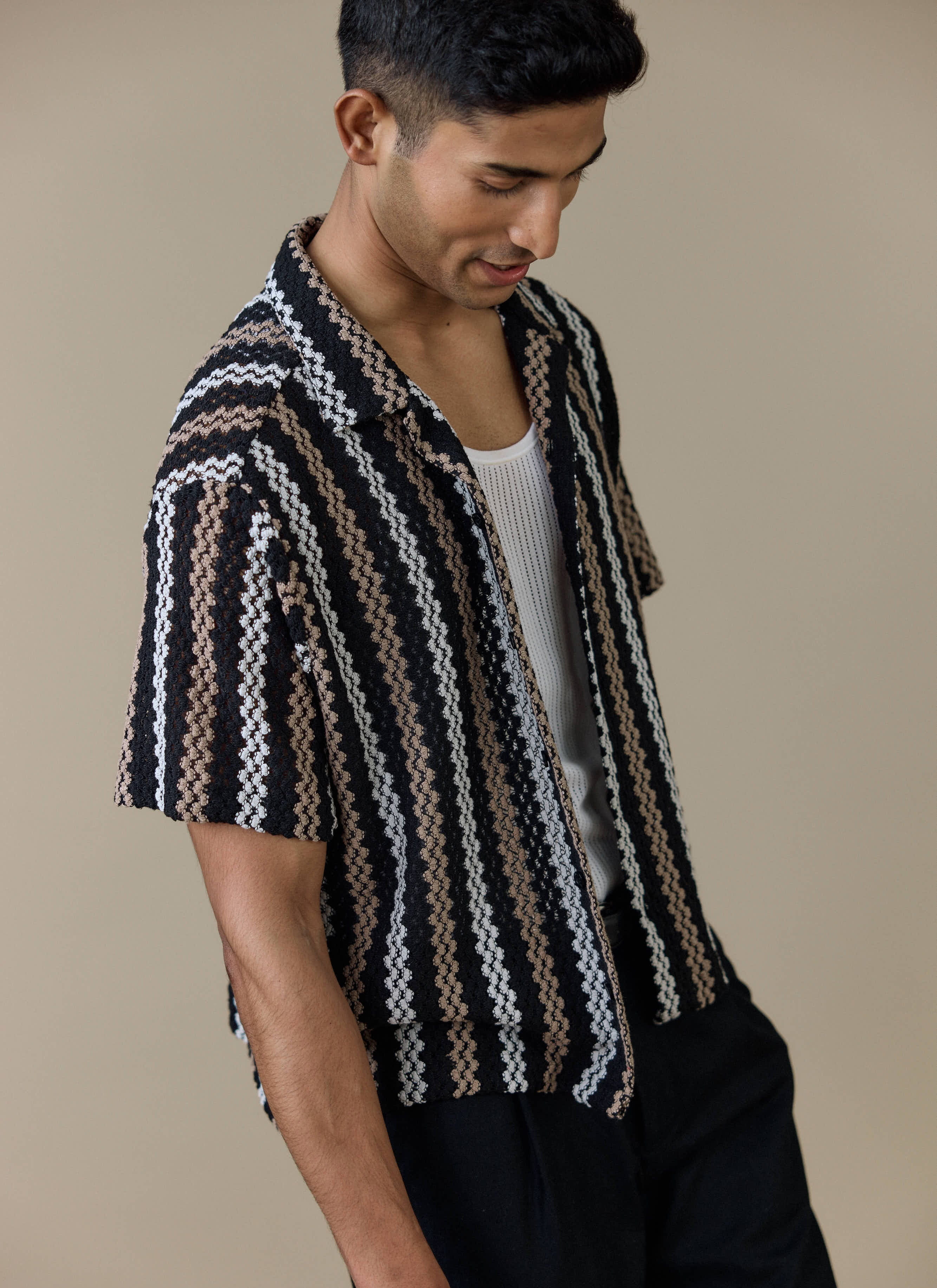 A model wears the black Percival Wade Crochet Boxy Shirt, featuring a textured open crochet stripe pattern.