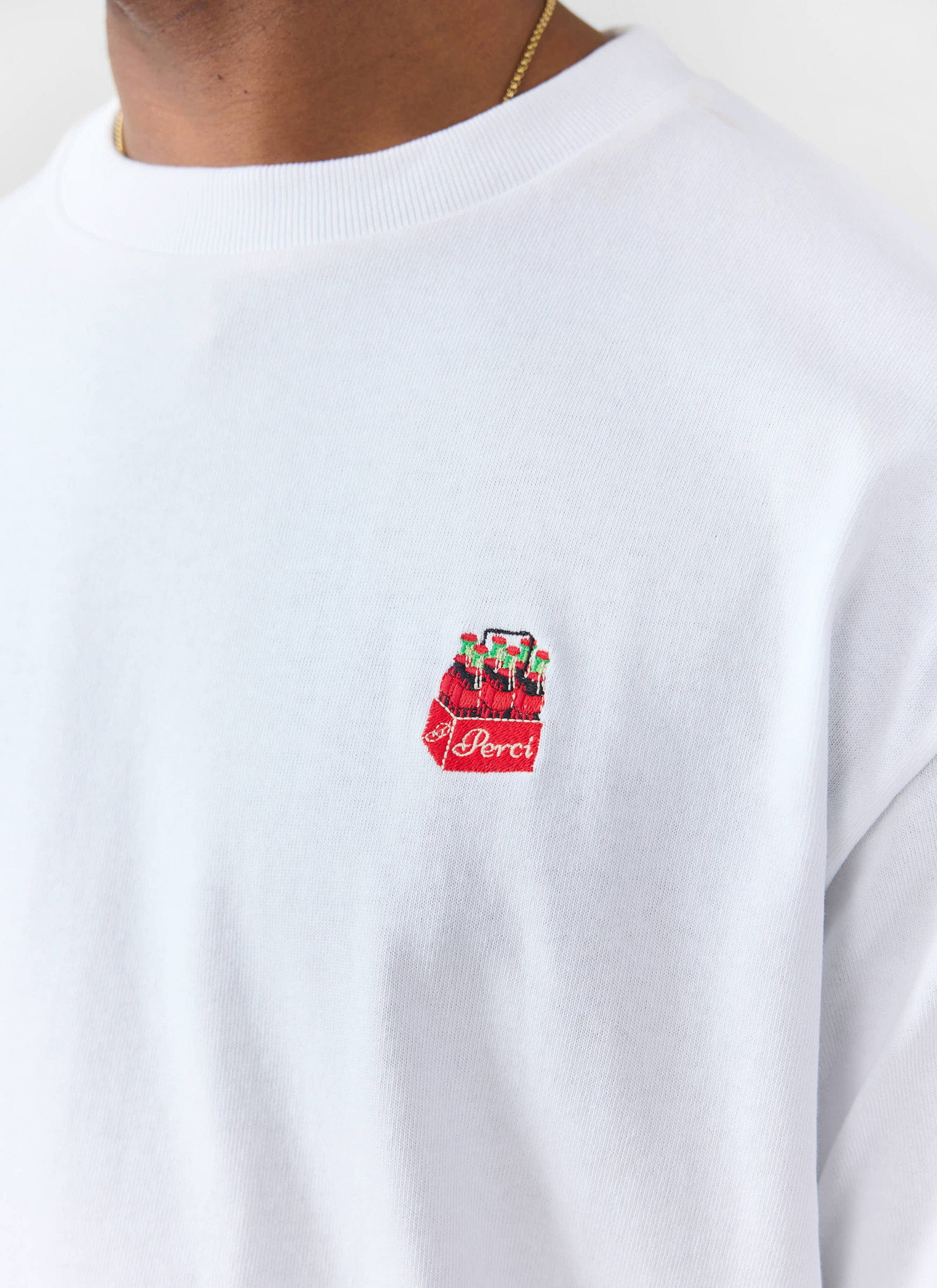 A detailed close-up of the soda bottle crate embroidery on the chest of the white organic cotton t-shirt by Percival.