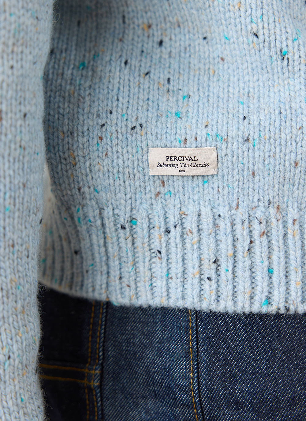 Close-up of the blue speckled Percival Rhodes White Glove Crew Neck Jumper, showing the textured weave and woven brand label.