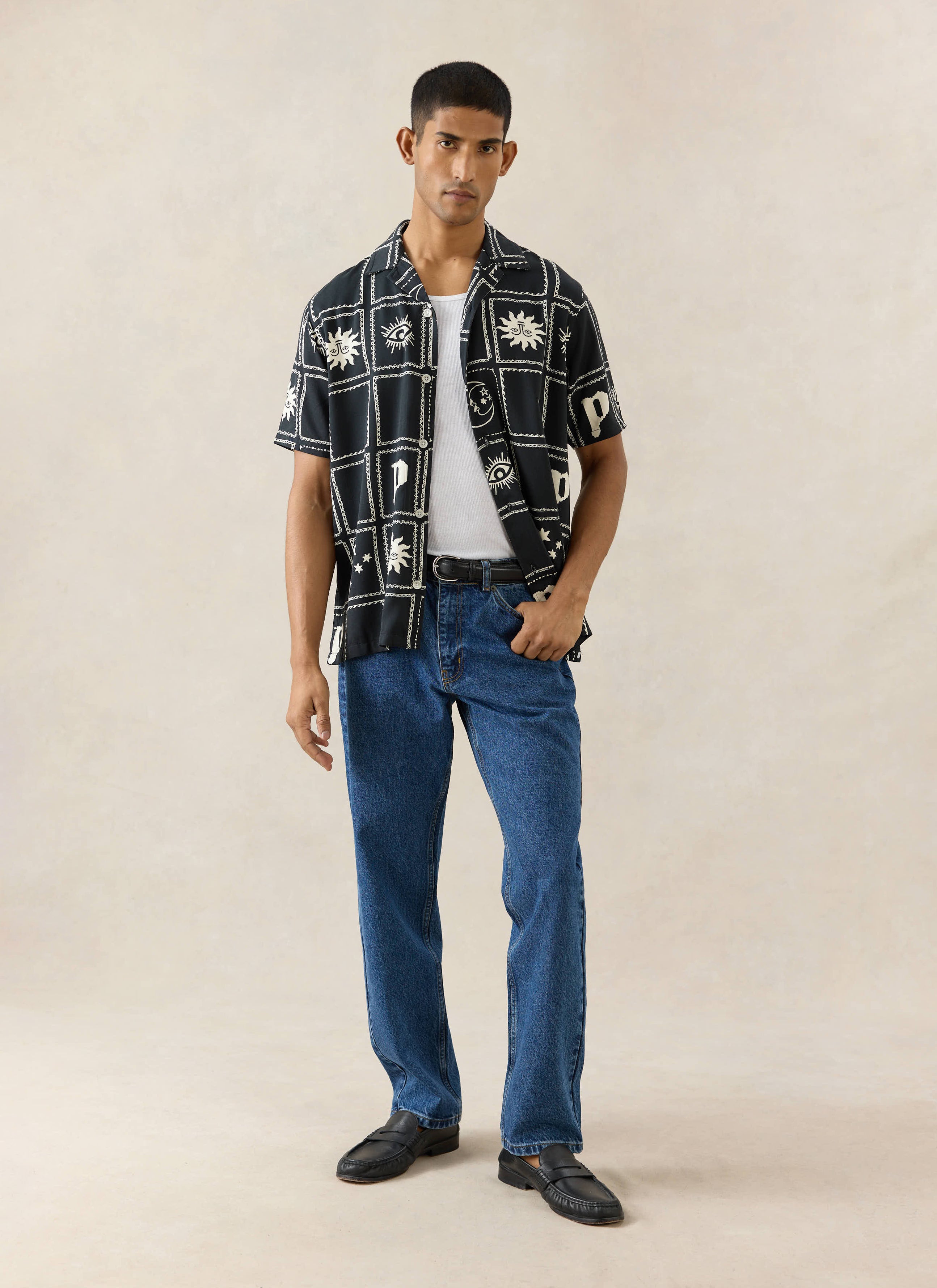 Percival Lunar Panel Cuban Shirt in black viscose with white celestial prints, styled with blue jeans on a model.