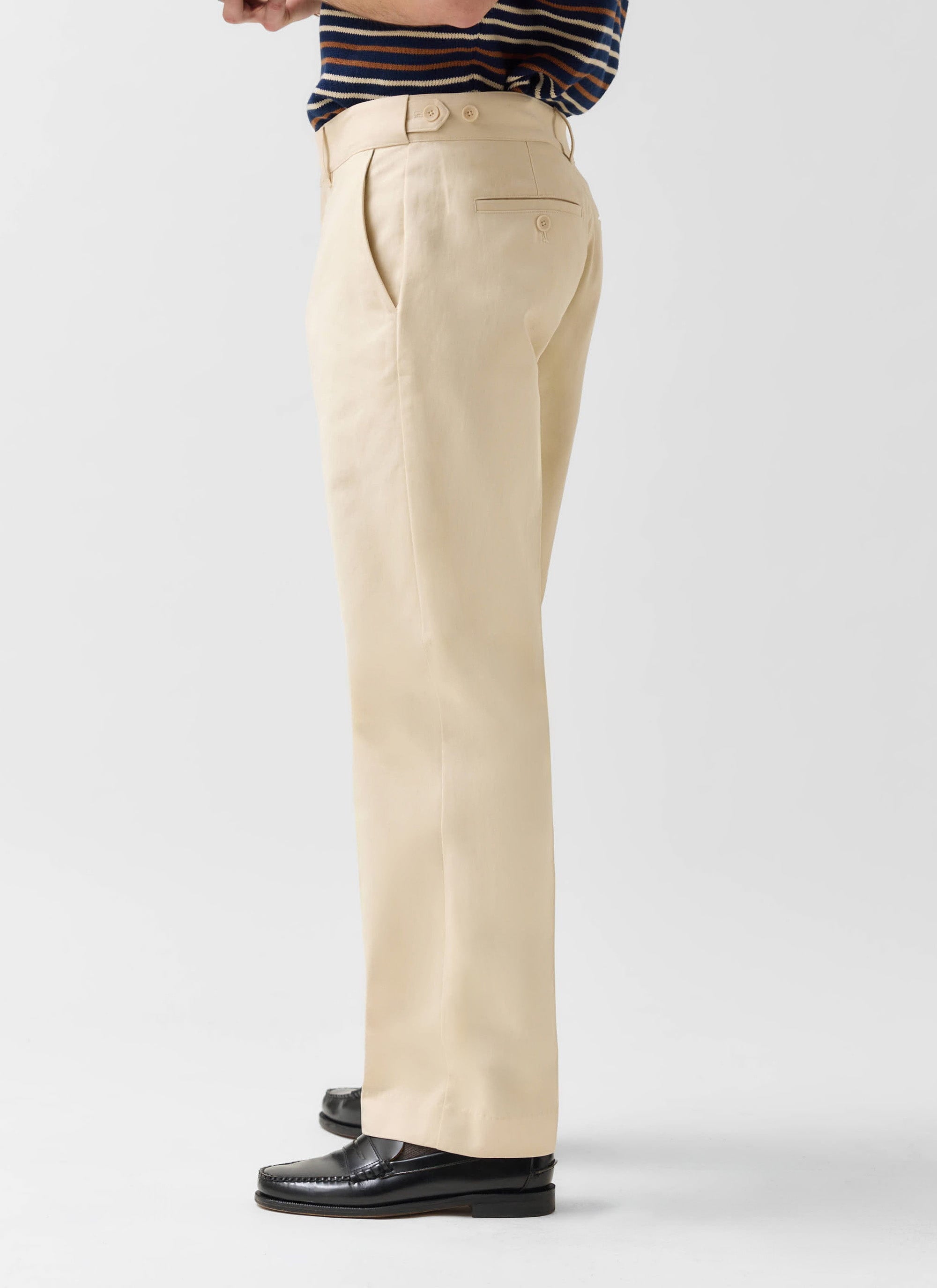 Side view of a model in the Percival Straight Leg Chino in ecru, paired with a striped top and black leather loafers.