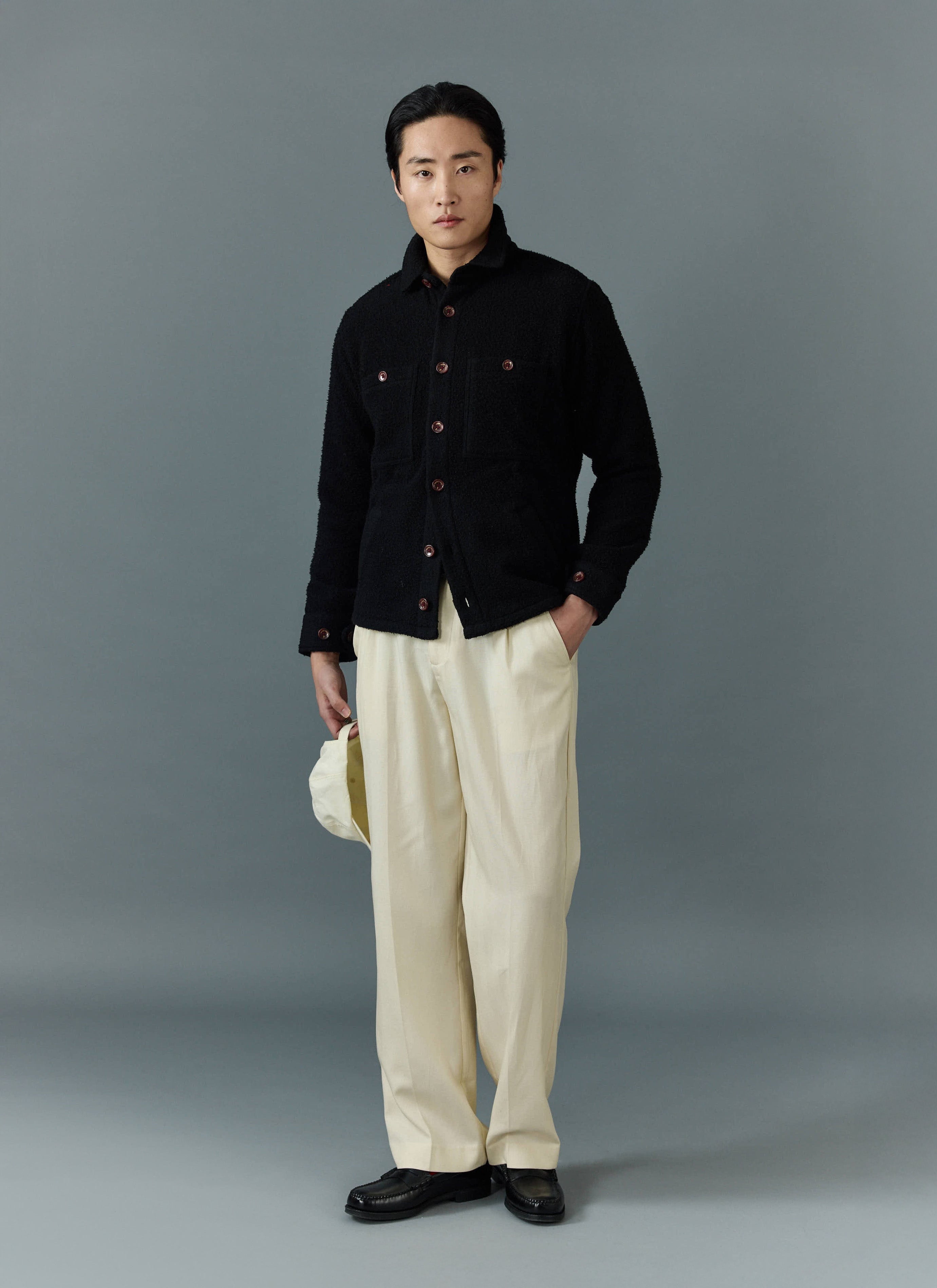 Full length shot of a model wearing the Percival black Casentino wool overshirt with cream trousers.