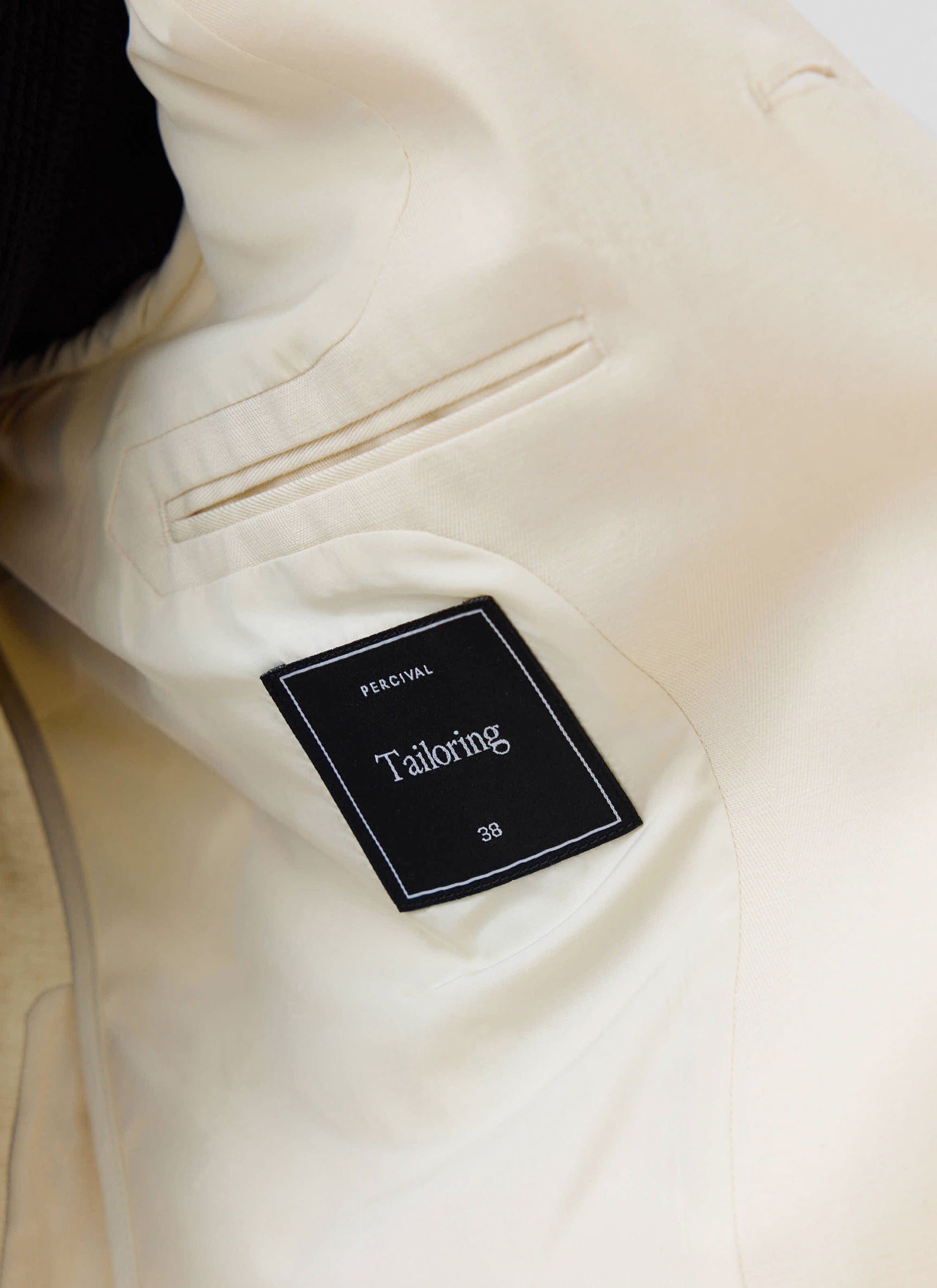 The internal 'Tailoring' label and pocket detail inside the cream Clifton 3 Button Blazer by Percival.