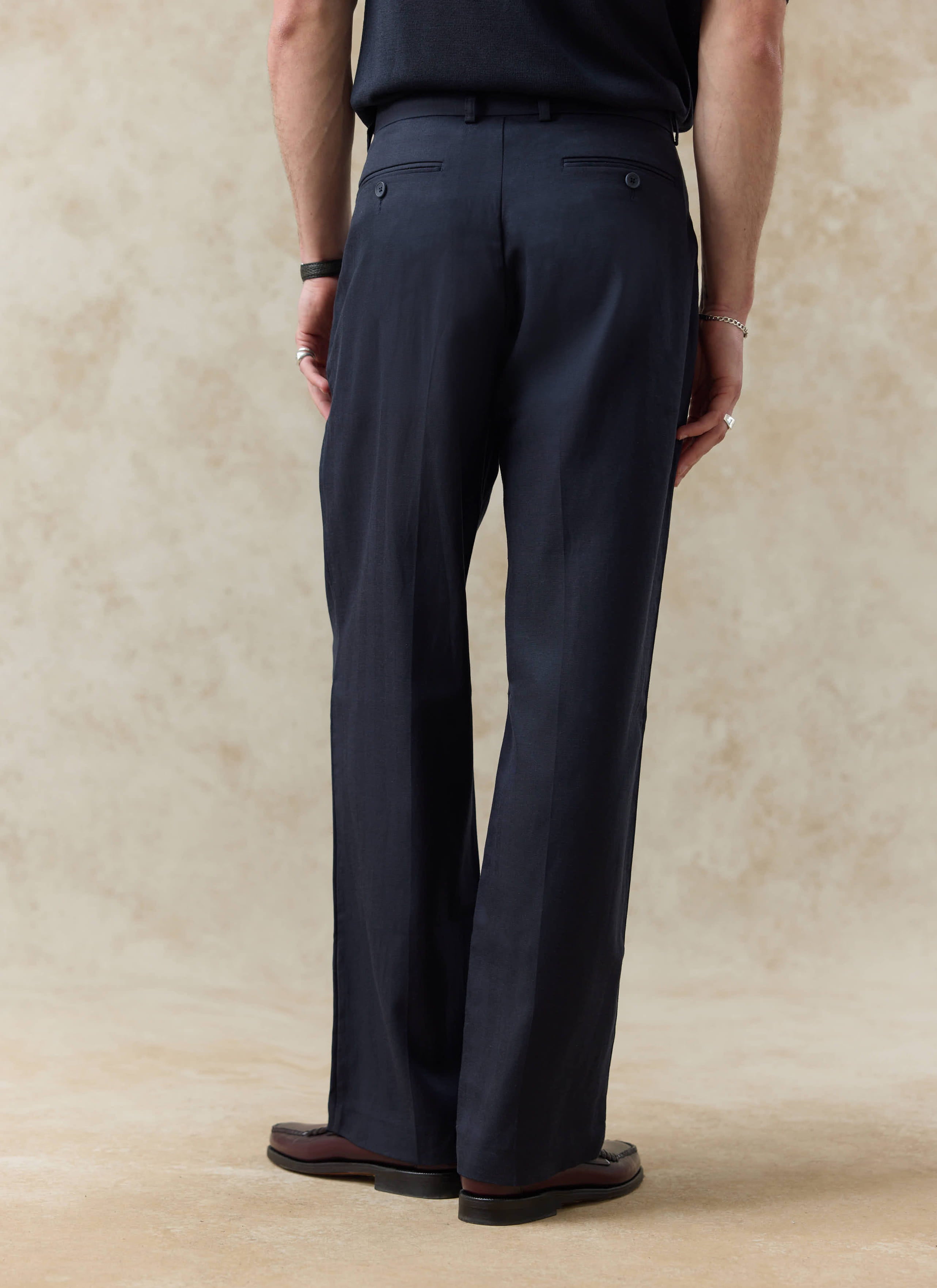 Rear view of Percival navy blue lyocell pleated leg trousers, showing the relaxed tailored fit and soft fabric drape.