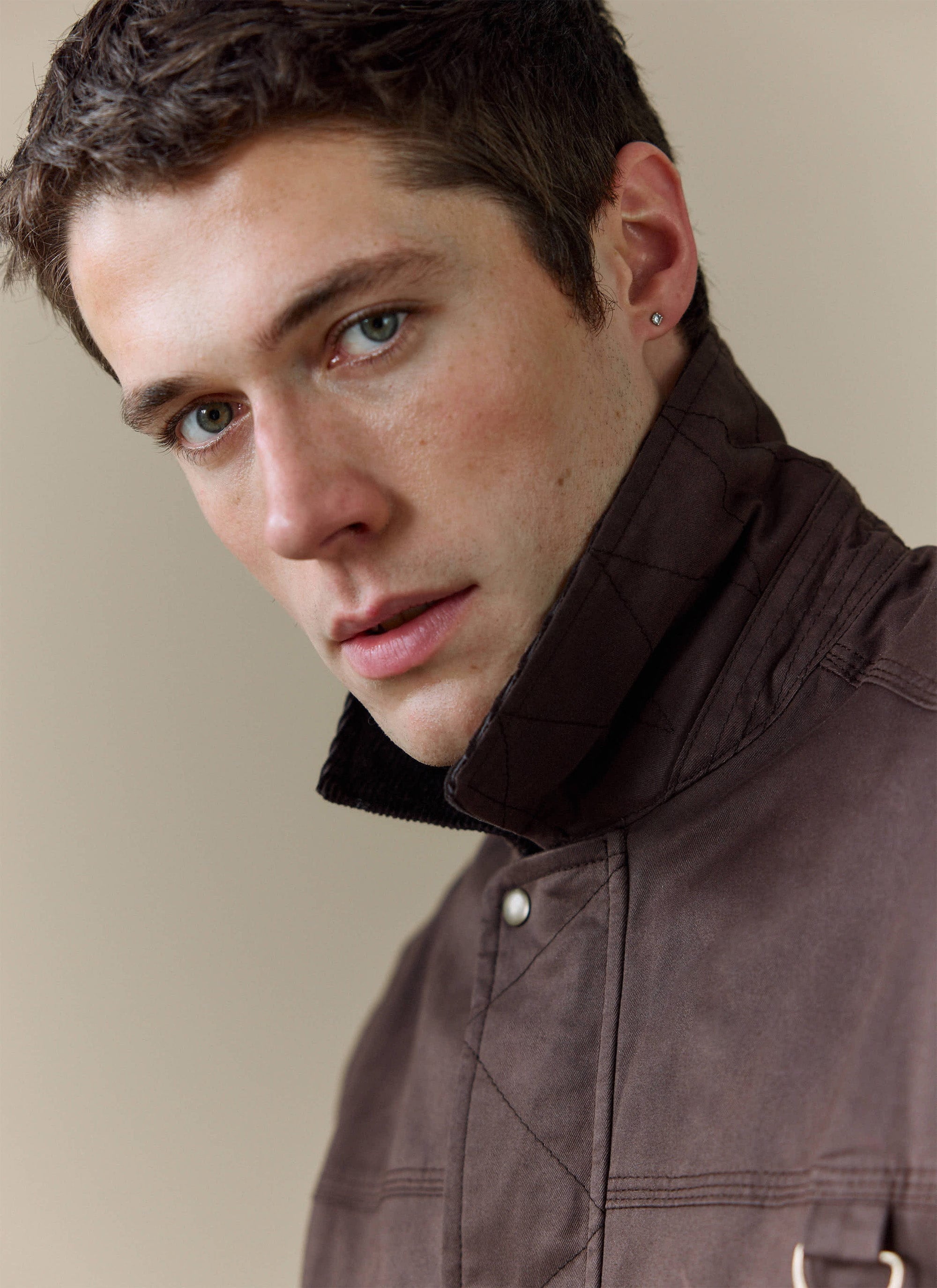 Close-up portrait of a model wearing the Percival espresso brown cotton wax zip jacket with a structured collar.