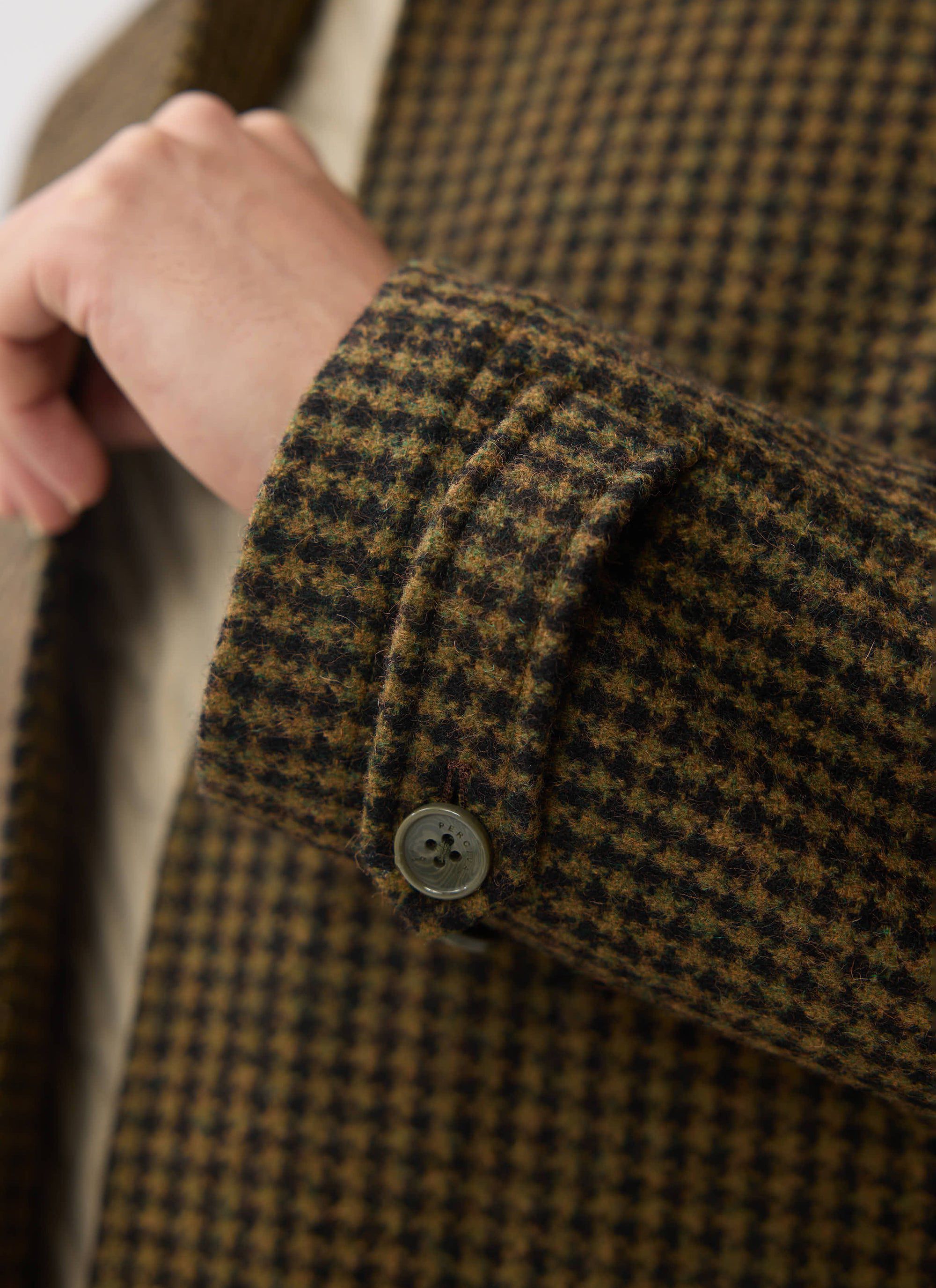 Close-up of the sleeve cuff on the Percival Dickens Car Coat, showing the brown houndstooth wool and branded button.