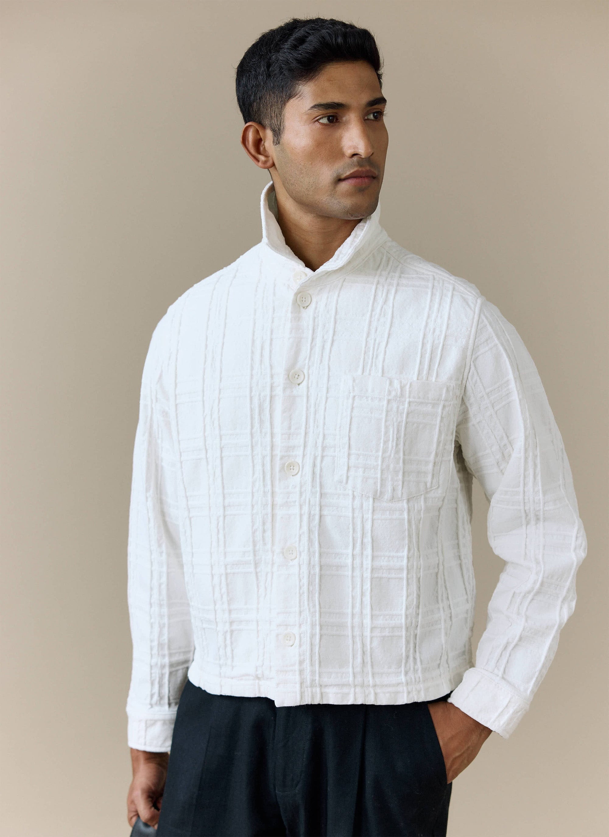 A model wears the Percival Canyon Heavyweight Overshirt in ecru, a textured jacket styled with black trousers.