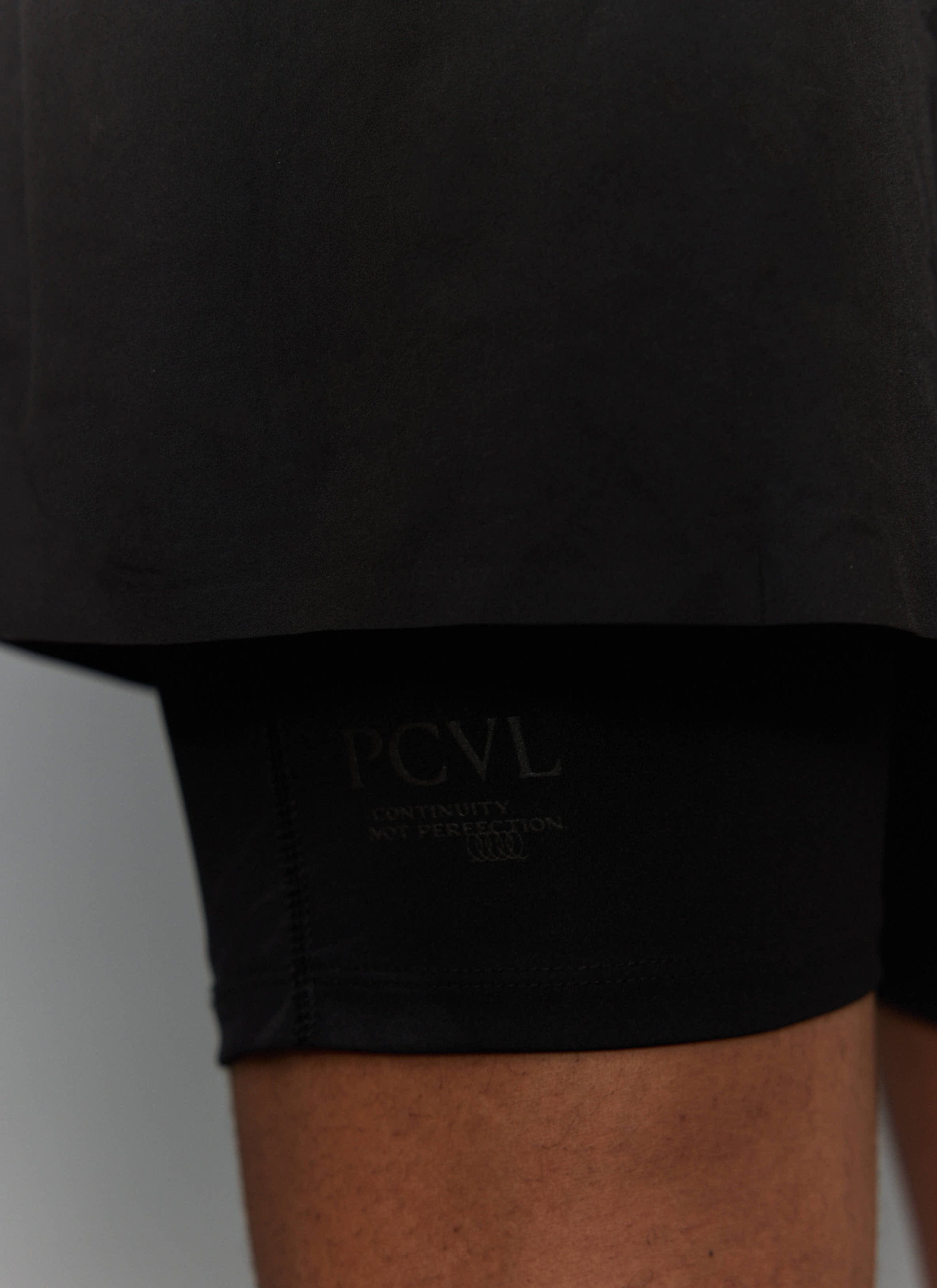 Close-up of the black PCVL 2 in 1 Shorts from Percival, showing the tonal branding on the inner compression layer.