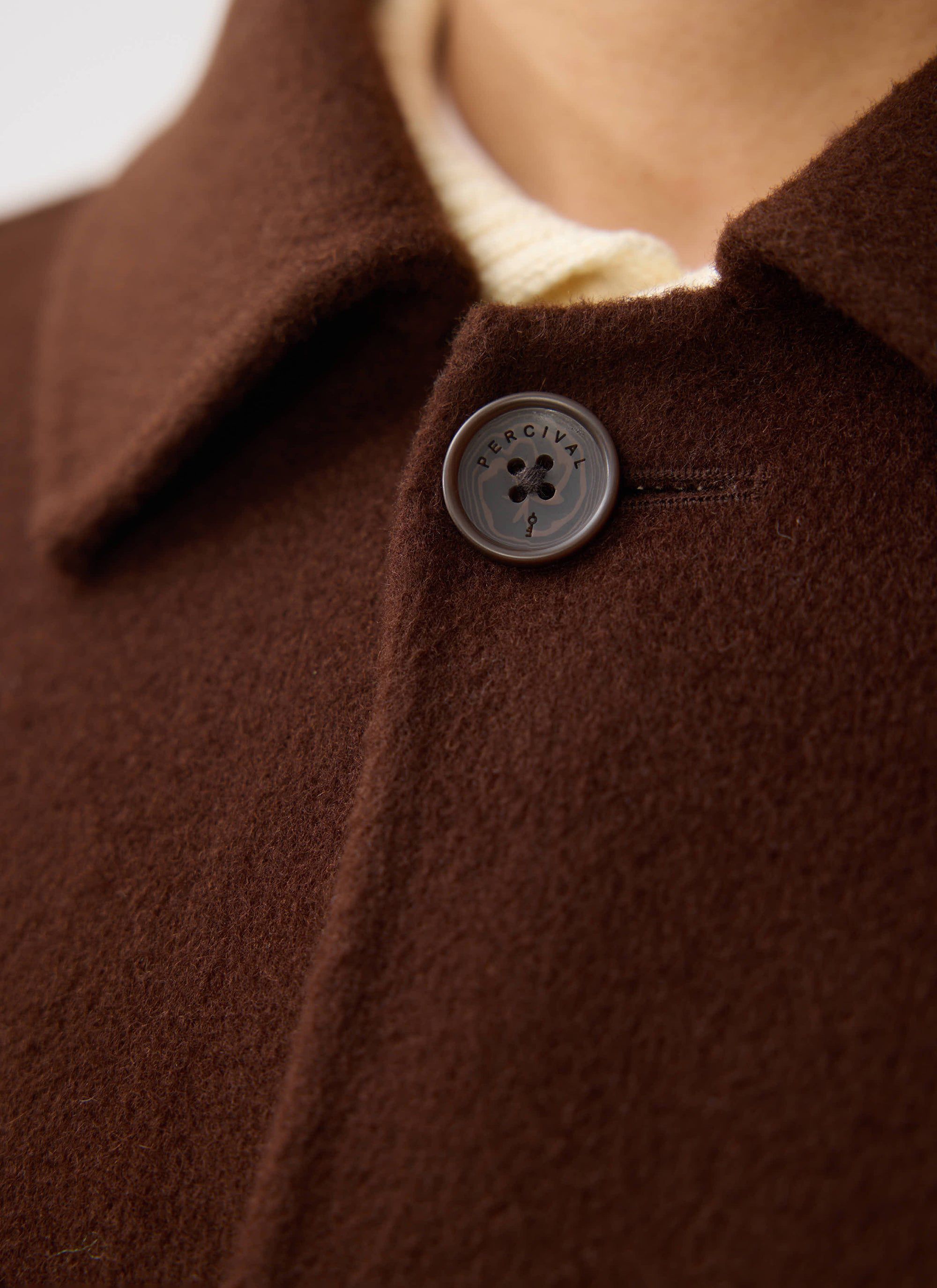Close-up detail of the Percival Minnesota Overcoat in espresso wool, focusing on the branded button and textured fabric.
