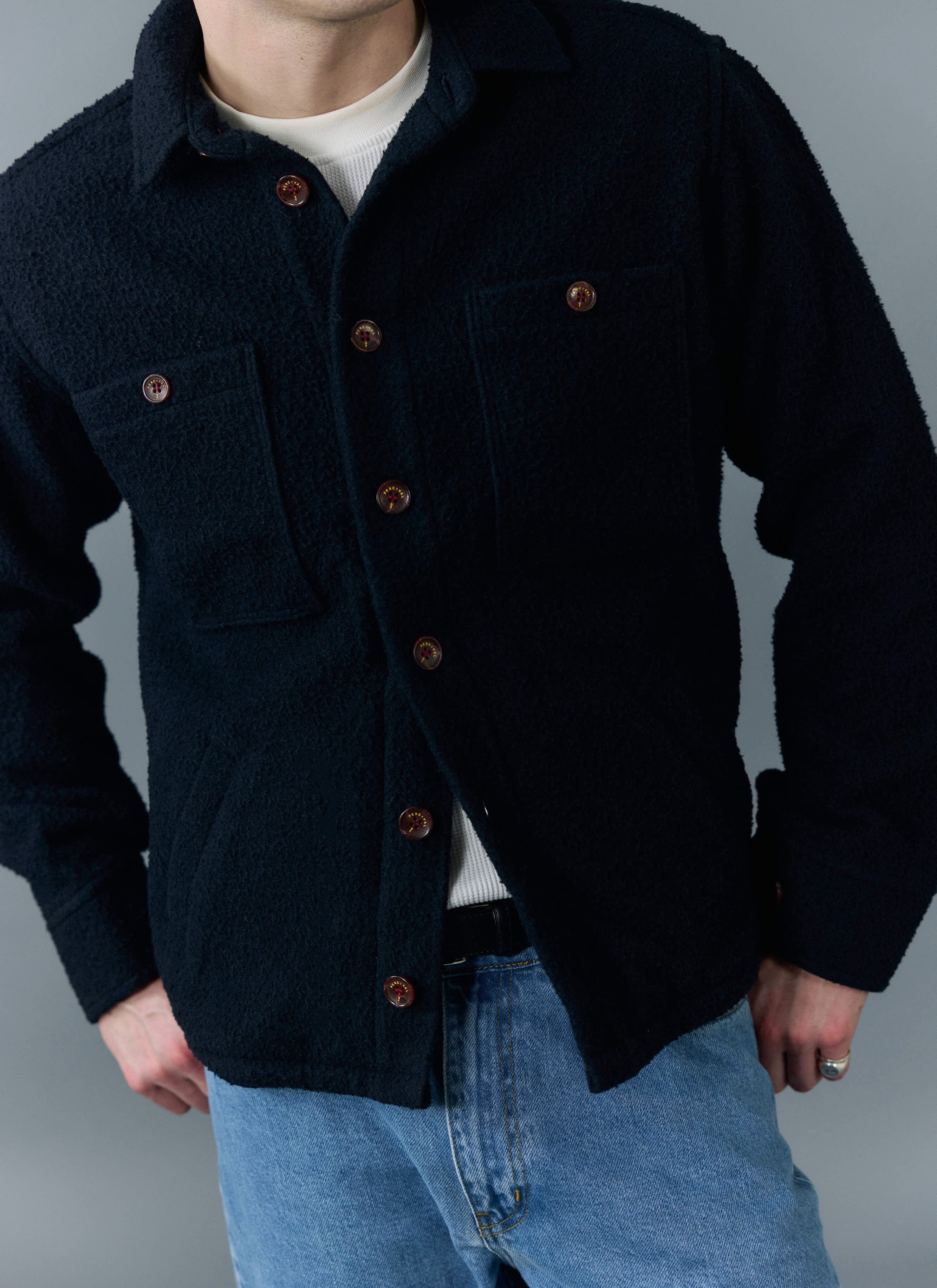 A model wears the Percival Blanket Overshirt in navy Casentino wool over a white top and jeans.
