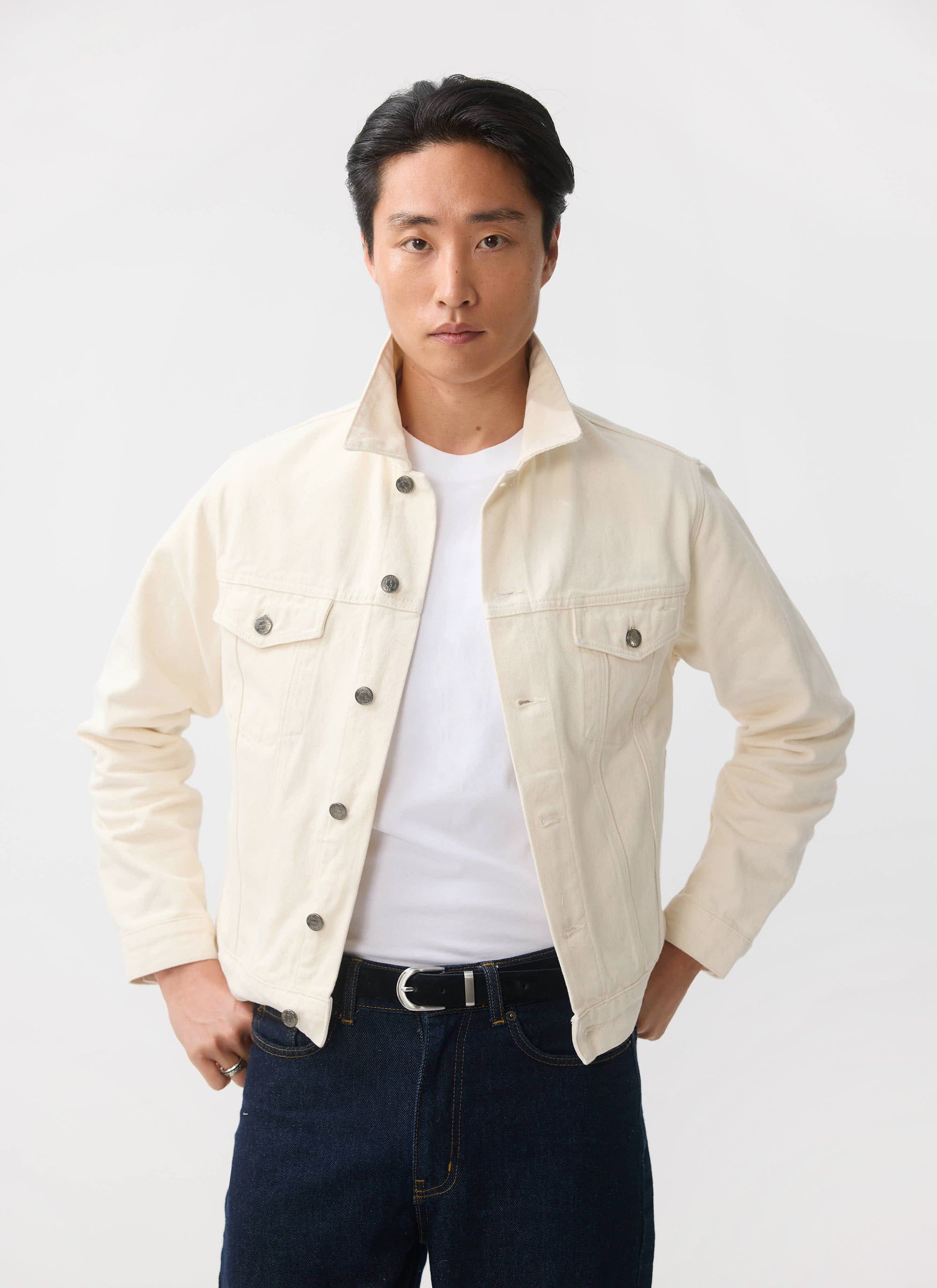 A man models the Percival ecru Western Trucker Jacket, styled open over a white tee and dark denim jeans.