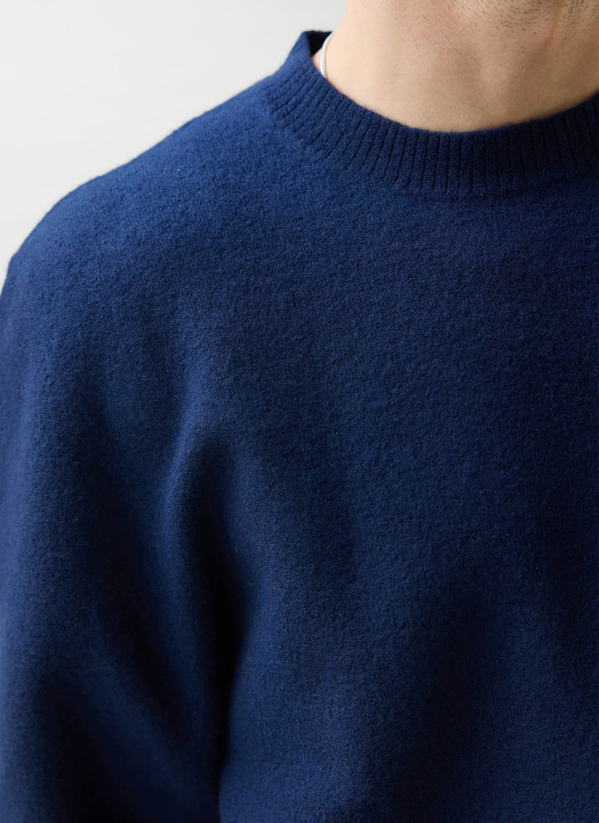 A close-up shot of the Percival Felted Regular Jumper in navy, highlighting the soft merino wool texture and ribbed collar.