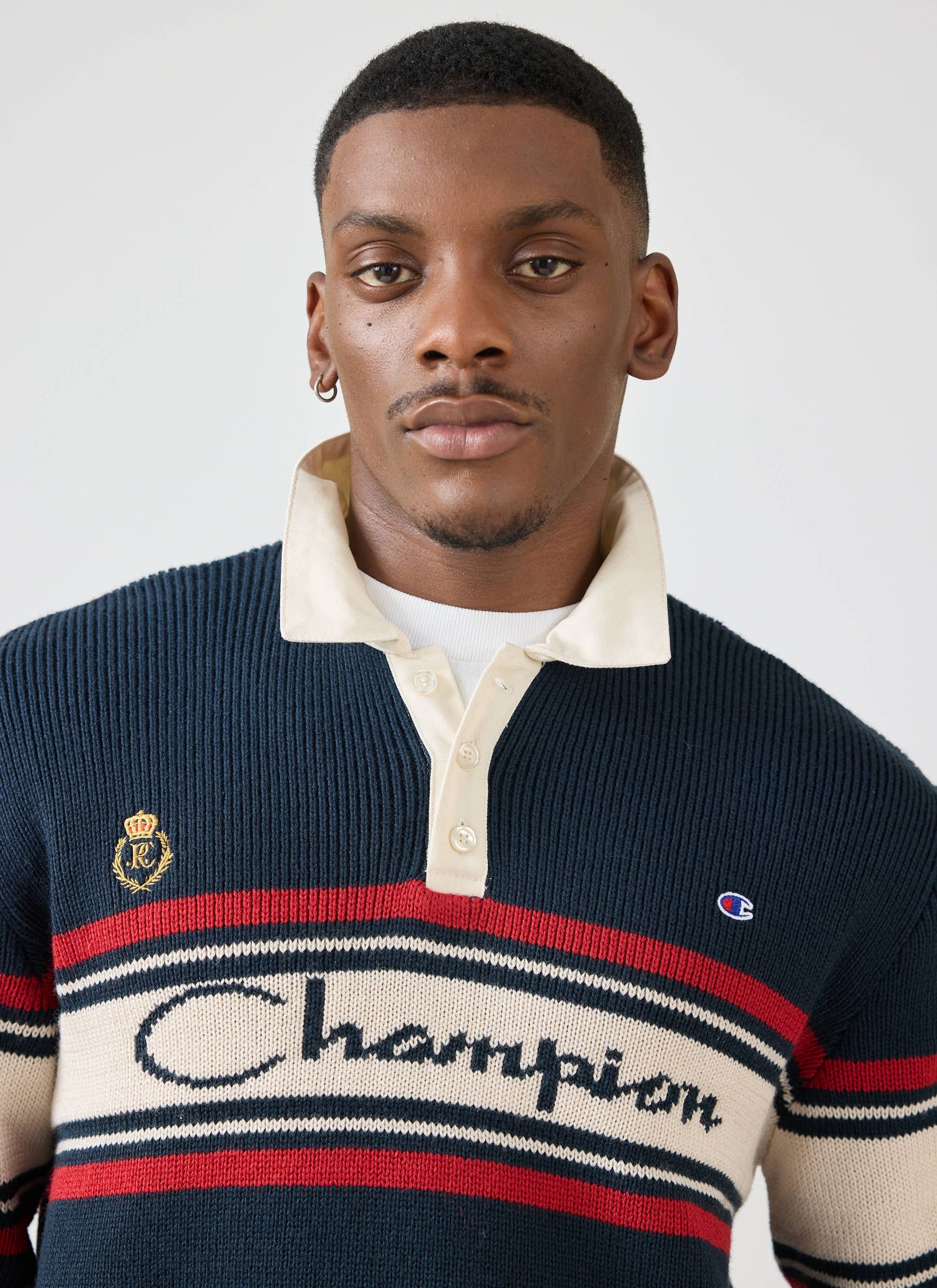 A close-up of a model wearing the navy Jacquard Knitted Rugby Polo Shirt from the Champion x Percival collaboration.