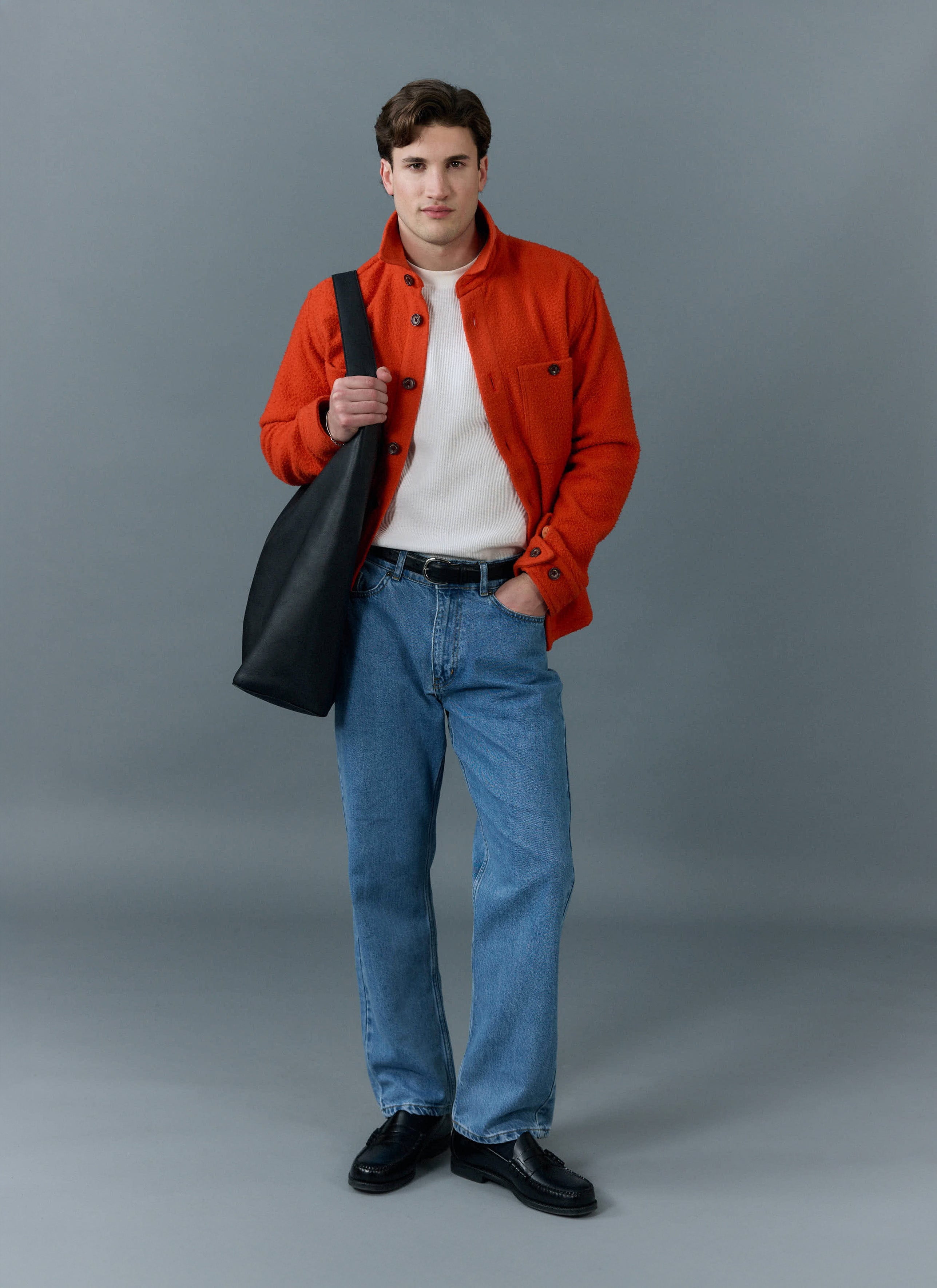 A model wears the orange Percival Blanket Overshirt in Casentino wool, styled with blue jeans and a white top.