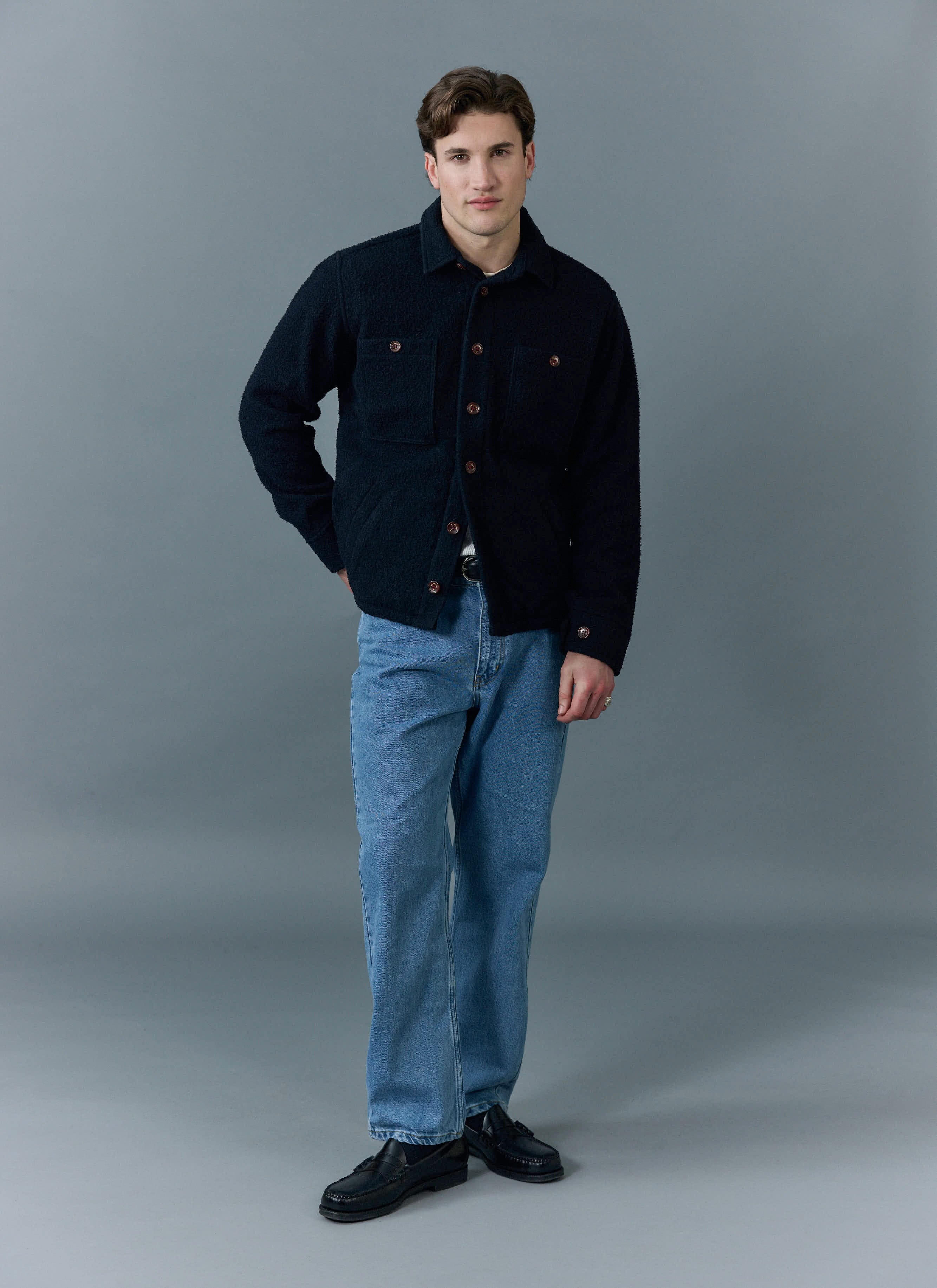 A model wears the Percival Blanket Overshirt in navy Casentino wool, styled with blue jeans and black loafers.