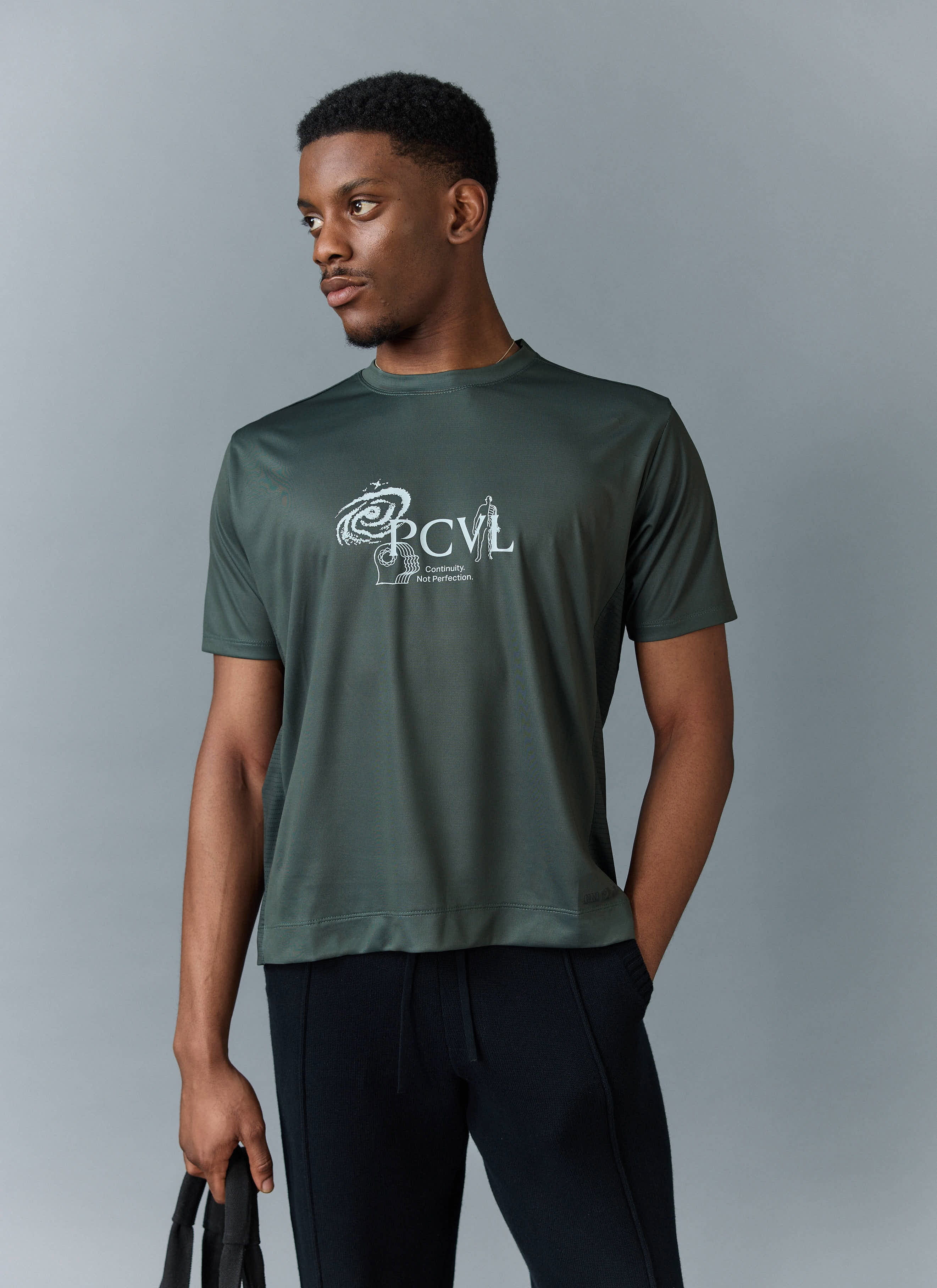 A model wears the Percival PCVL Printed Performance Top in forest green, showing the white graphic print on the chest.