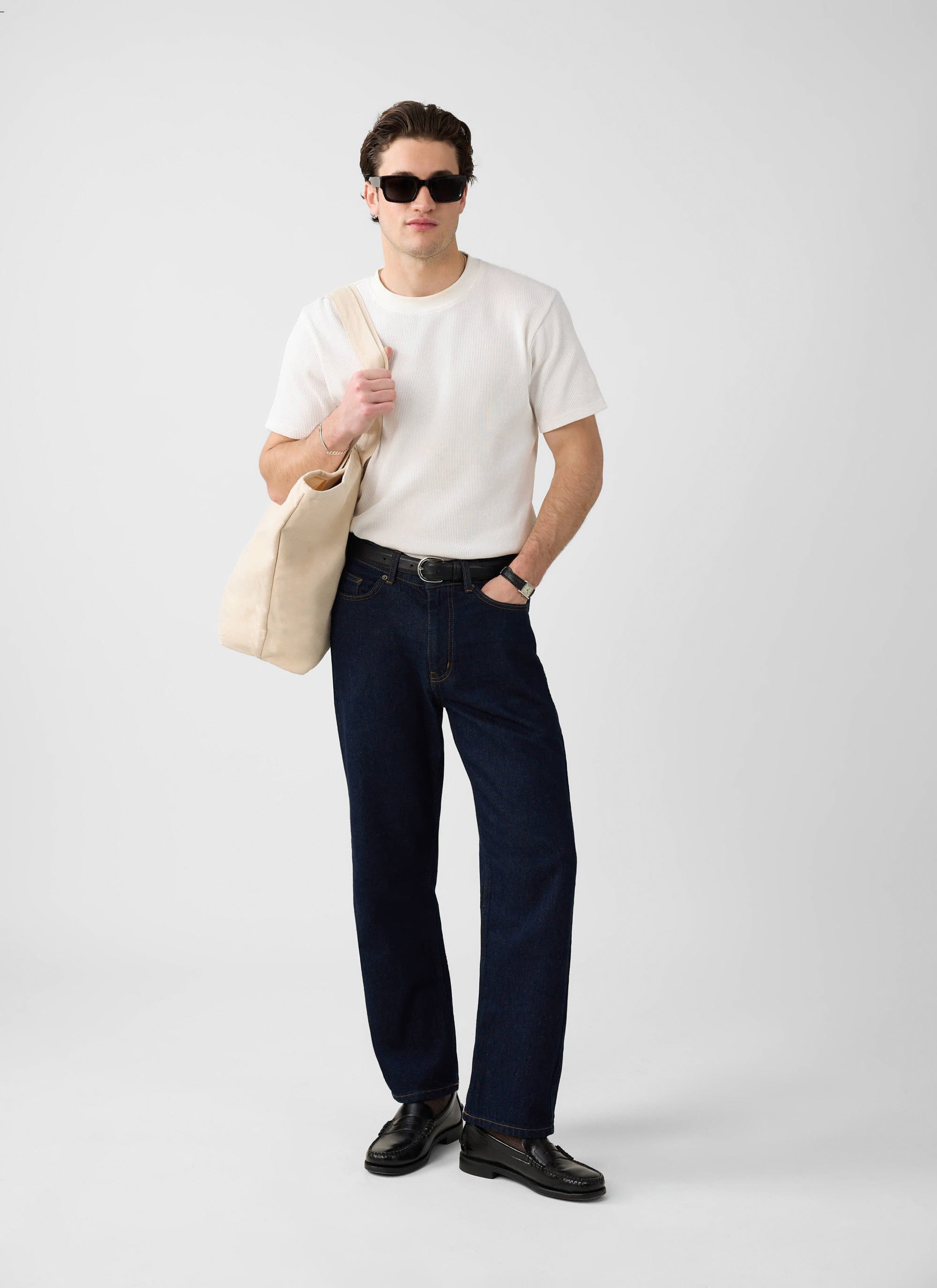 A model wears the Percival white Waffle Short Sleeve T-Shirt with dark wash jeans, black loafers and a cream tote bag.