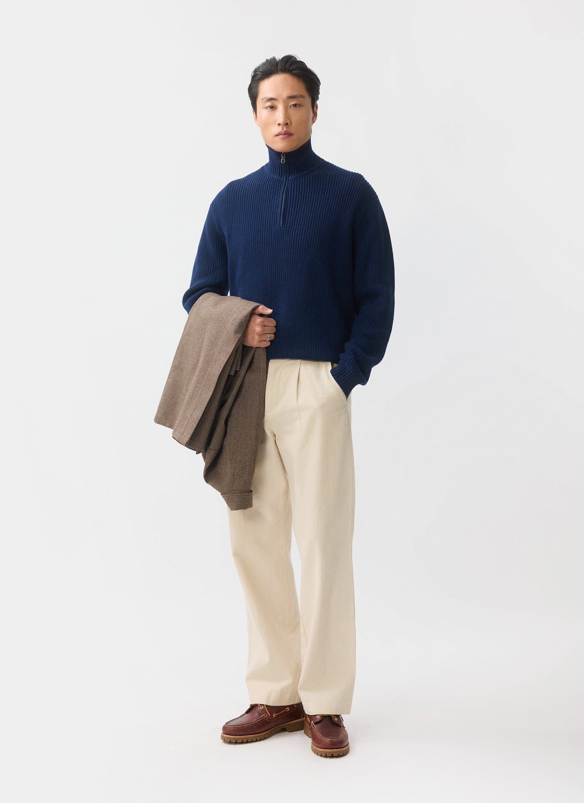 The Percival Meyer Quarter Zip Fisherman in blue, styled on a model with cream trousers and a brown jacket.