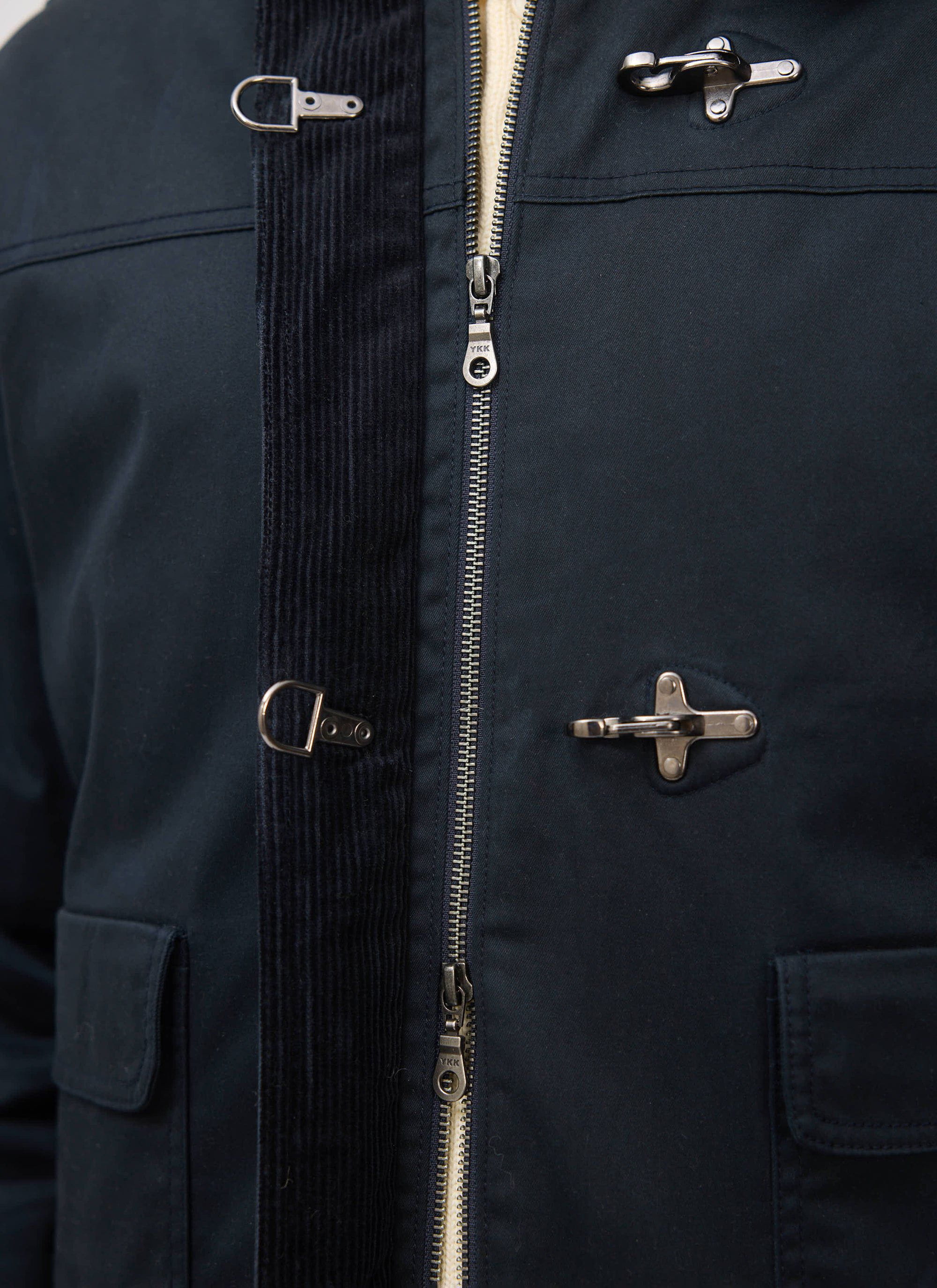A close-up of the Percival Fontane Wax Jacket in navy, showing the metal fireman clasp, zip, and corduroy details.