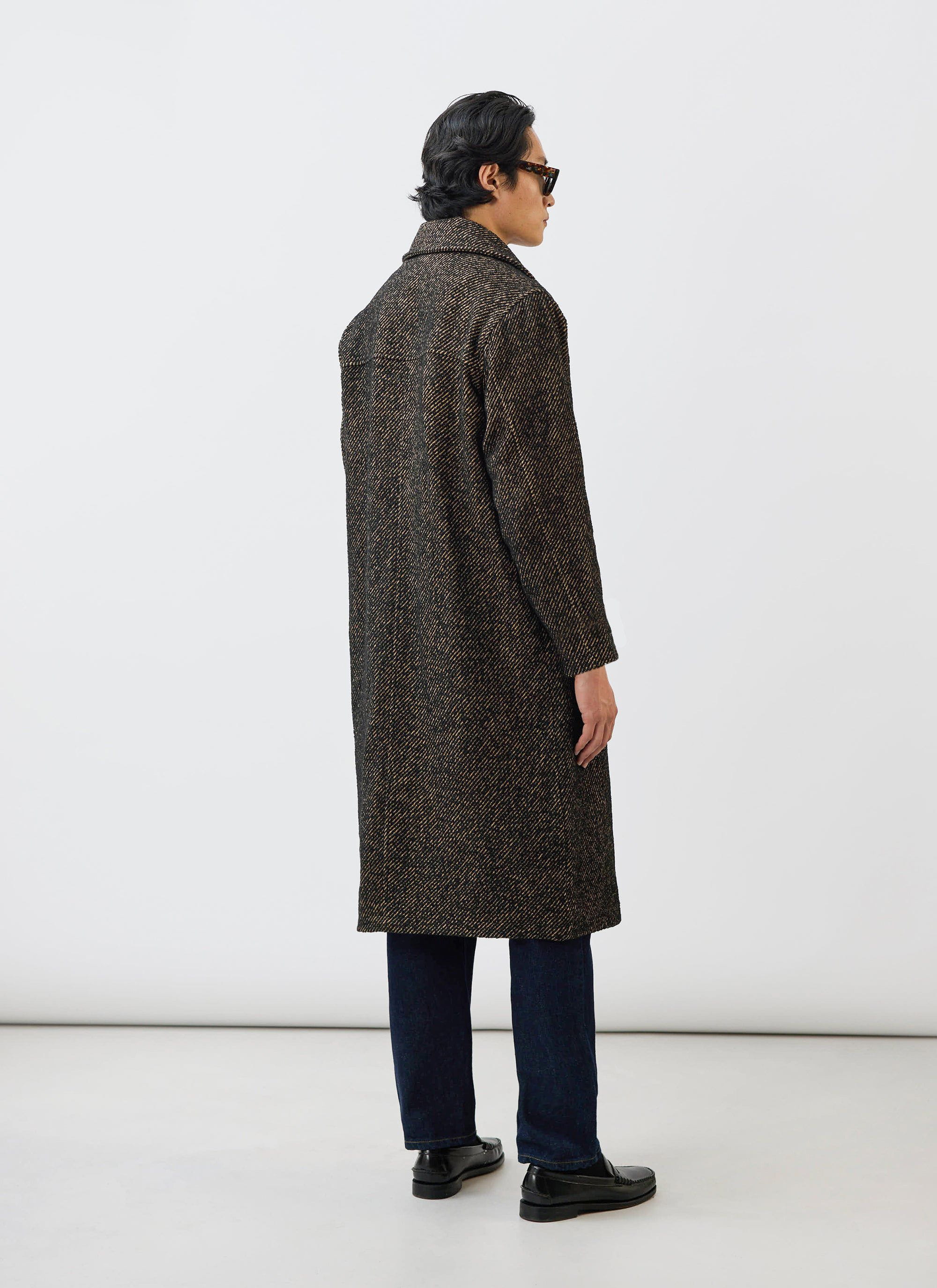 A model wears the Percival Minnesota Overcoat in Oak twill, styled with dark jeans and loafers, shot from behind.
