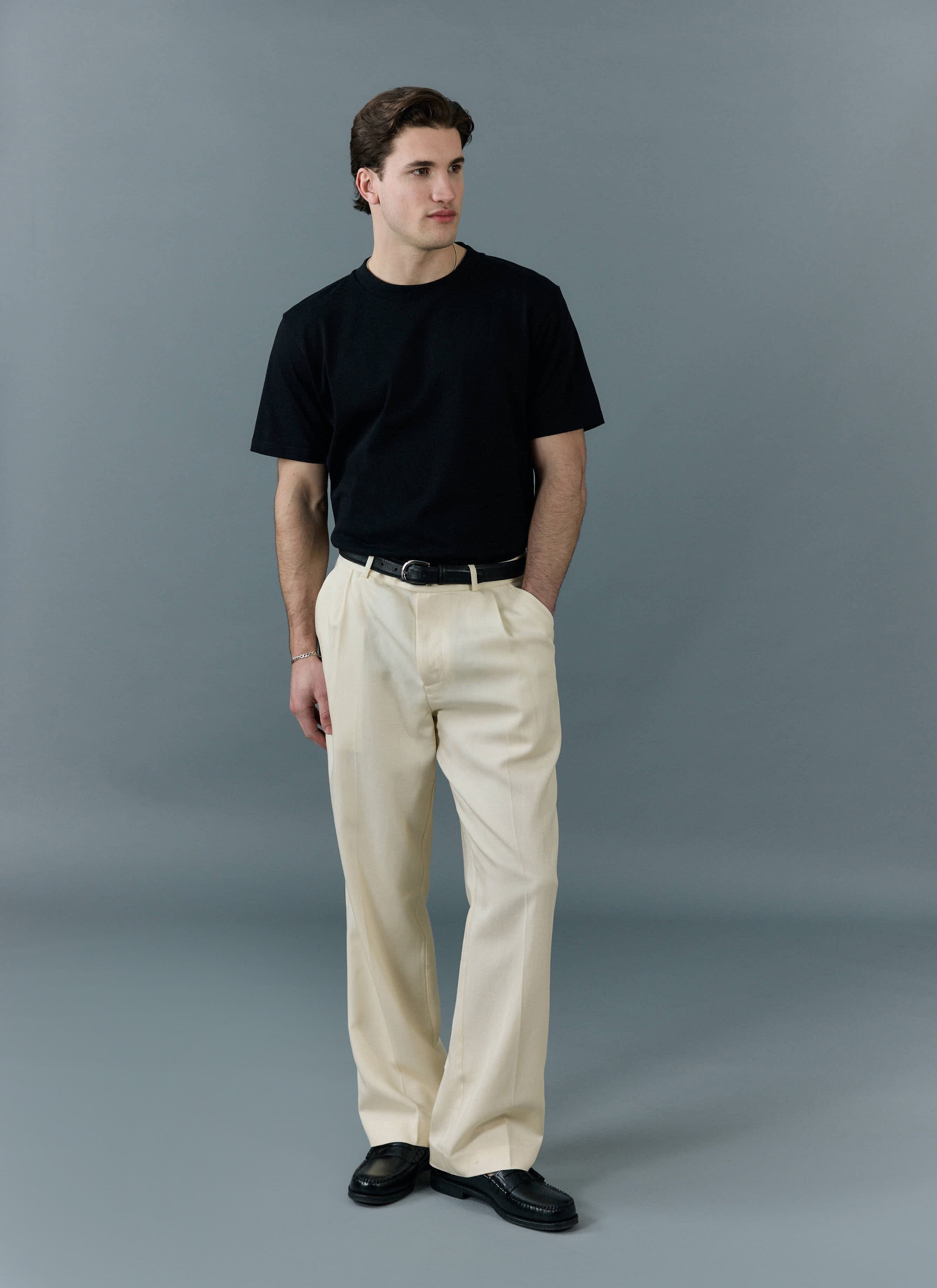 Model wears the Percival black regular fit organic cotton t-shirt with cream trousers and black loafers.