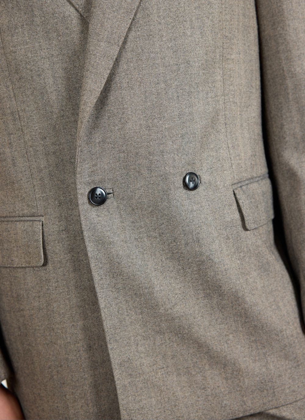 Close up shot of the Percival Tailored Double Breasted Blazer in grey herringbone, highlighting the fabric weave and buttons.