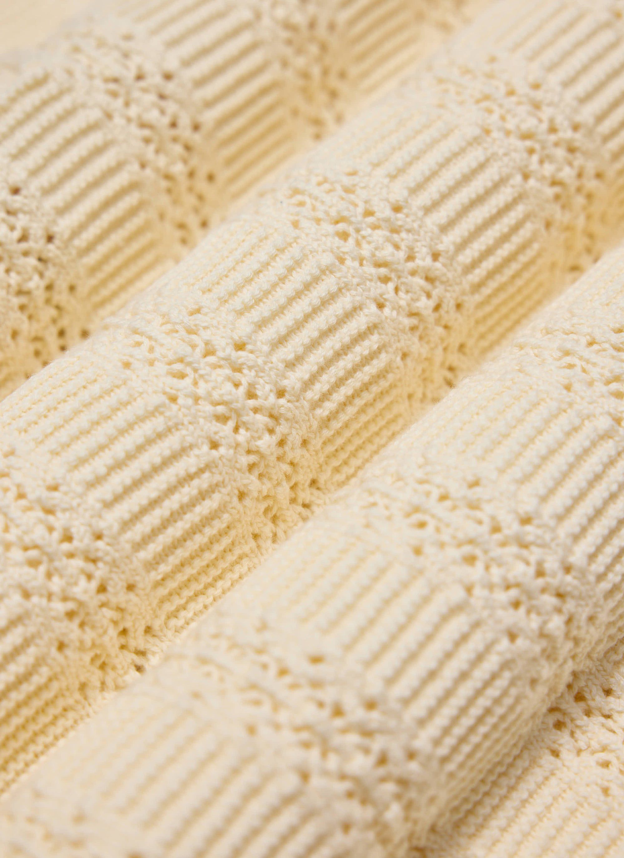 A close-up of the tonal book spine jacquard texture on the ecru Addendum Knitted Polo Shirt from Percival.