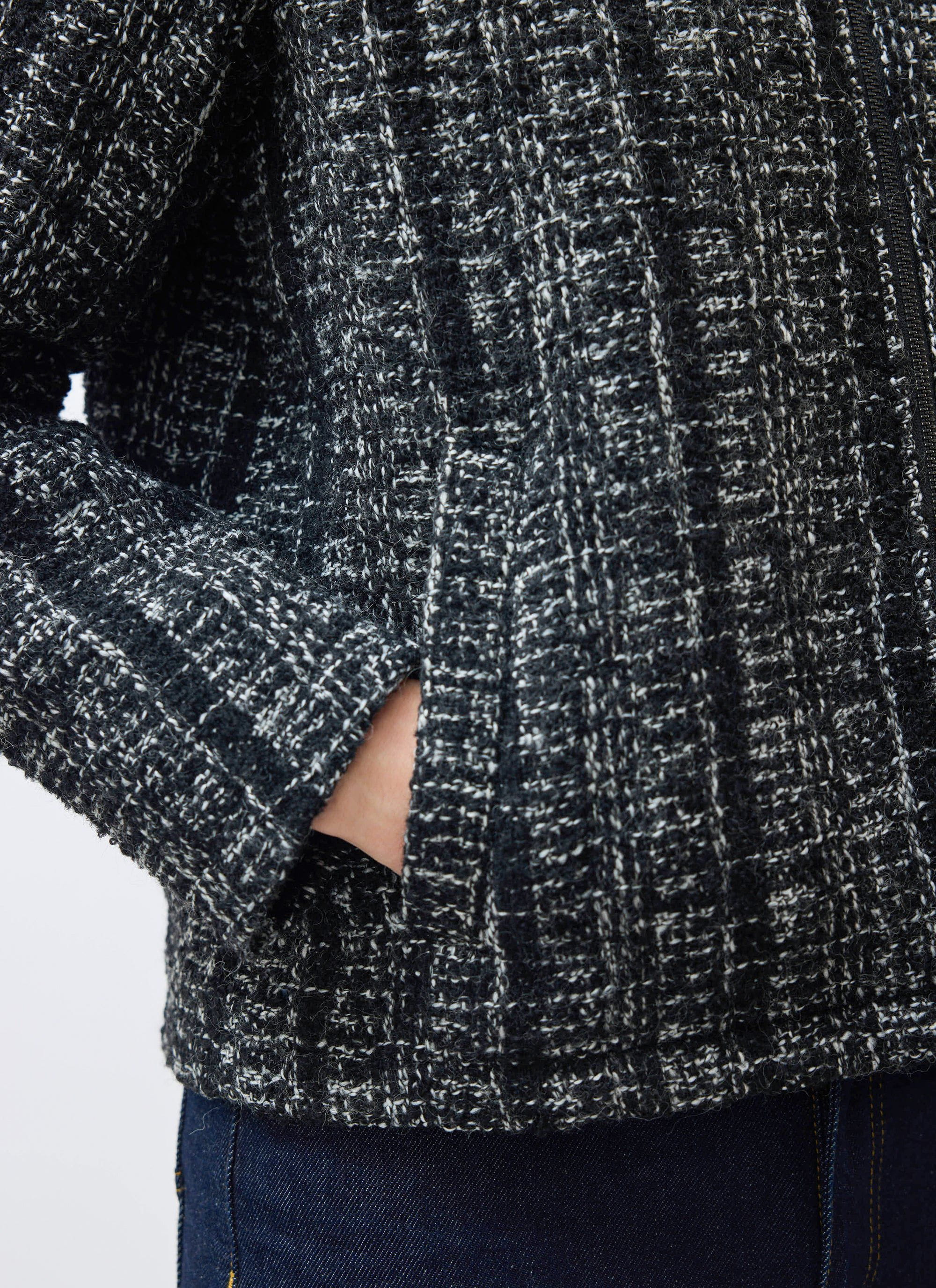 A close-up of the Percival Ingegno Zip Wool Boxy Jacket in black, detailing the bouclé tweed texture and the welt pocket.