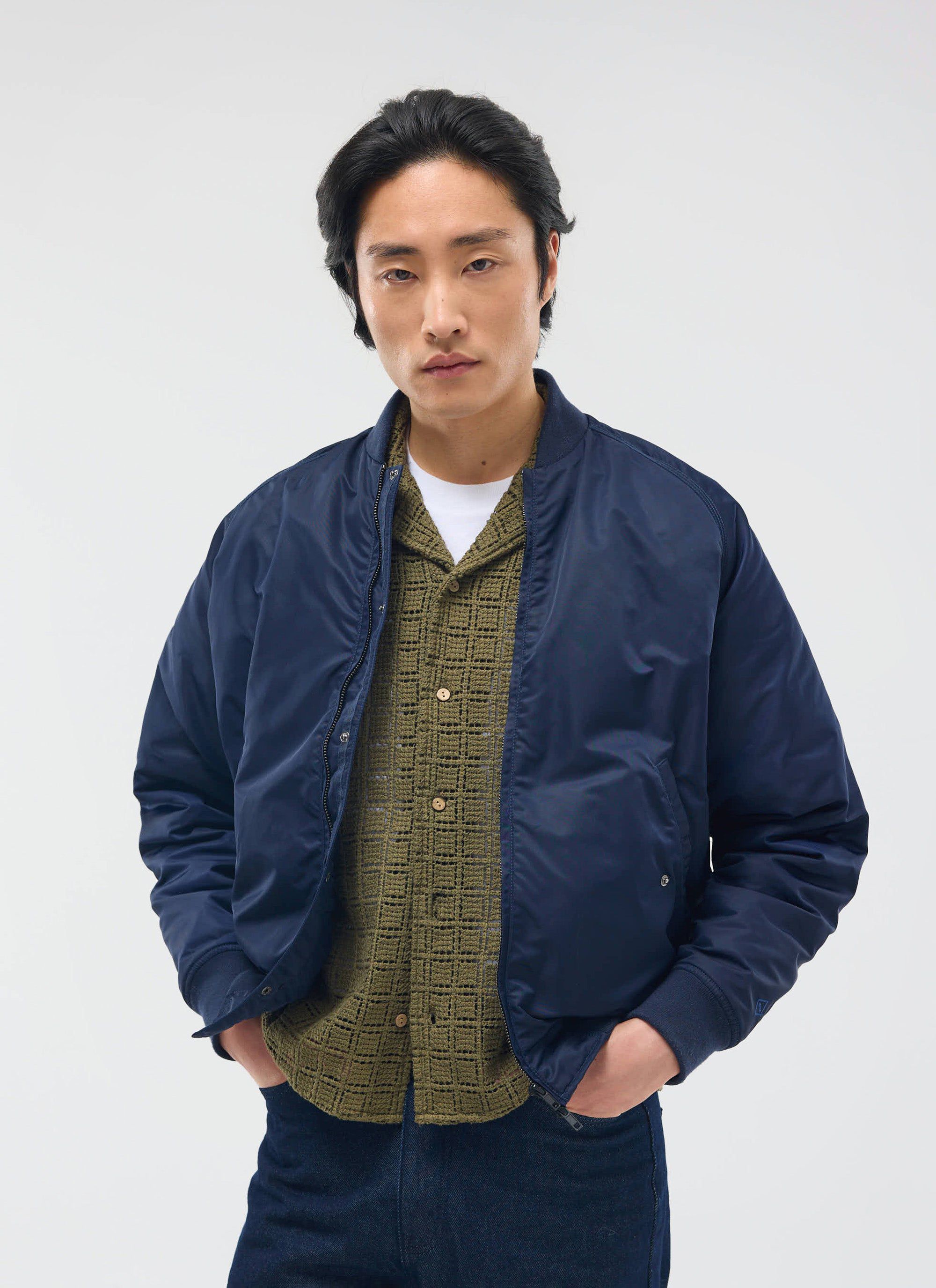 A model wears the Percival Palermo Crochet Cuban Shirt in olive green, layered under a navy bomber jacket.