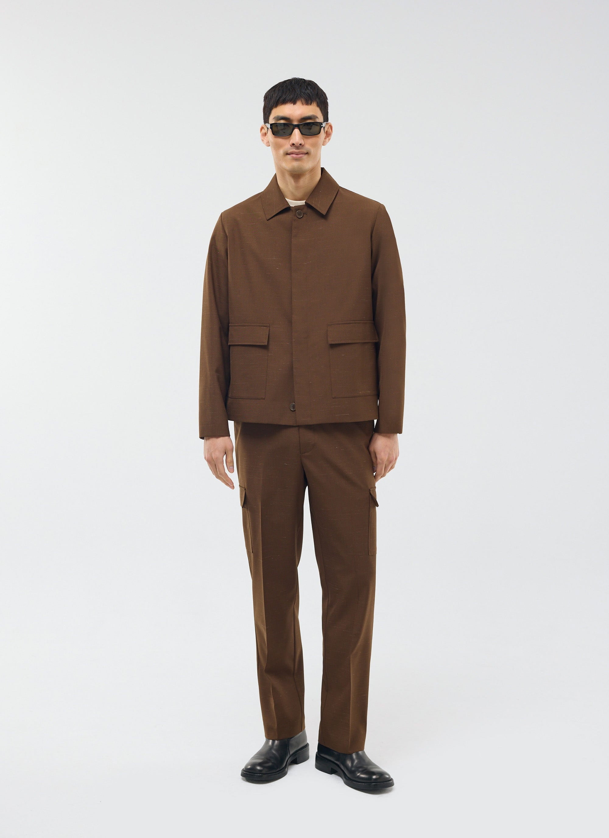 A model wears the Percival Trentino Tailored Patch Pocket Trousers in brown, styled as a full suit with sunglasses.