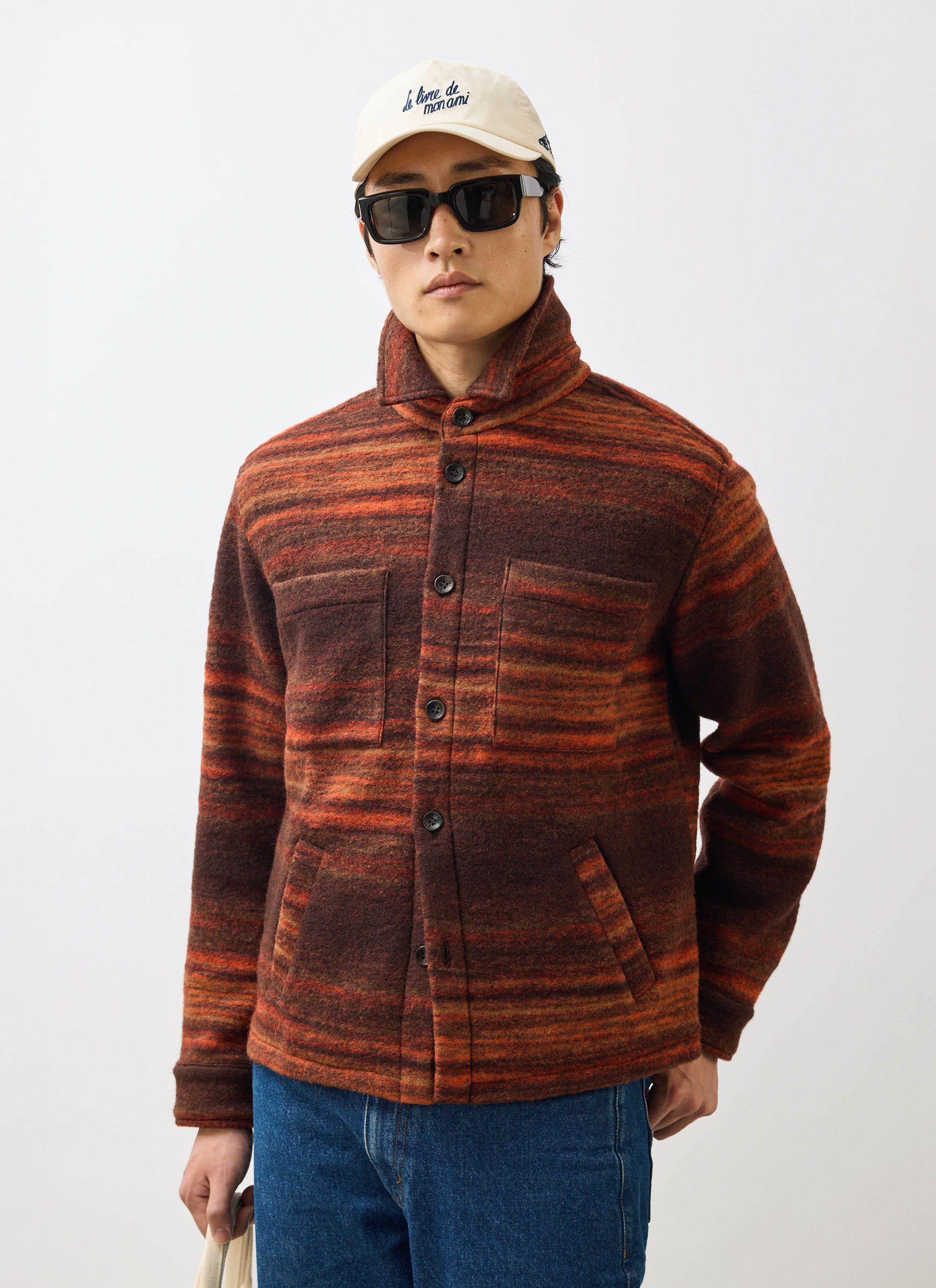 A model wears the Percival Mississippi Jacquard Overshirt in burnt orange and brown, styled with jeans and sunglasses.