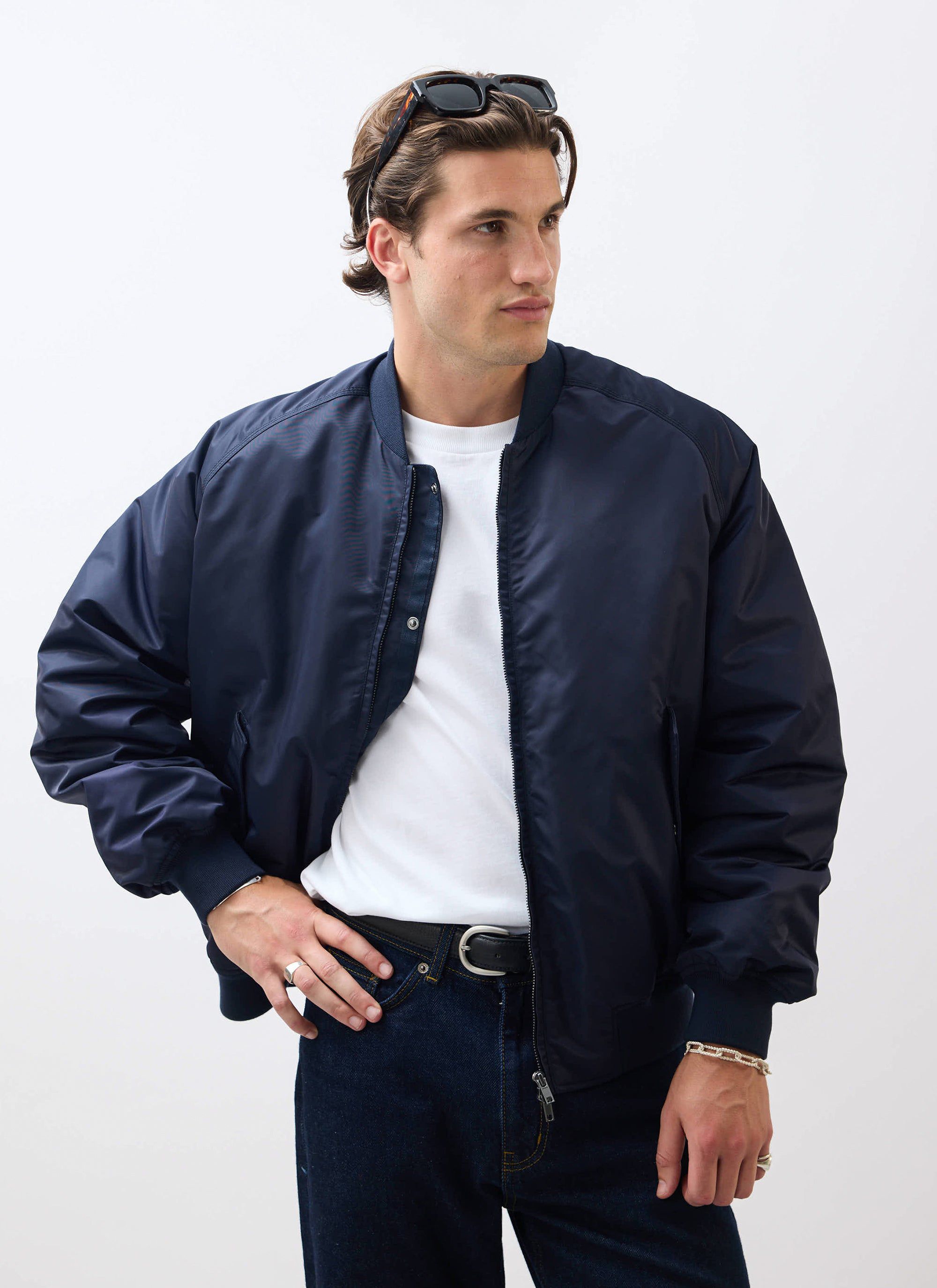 A model wears the Percival Nylon Bomber Jacket in midnight navy, styled open over a white t-shirt and dark denim jeans.