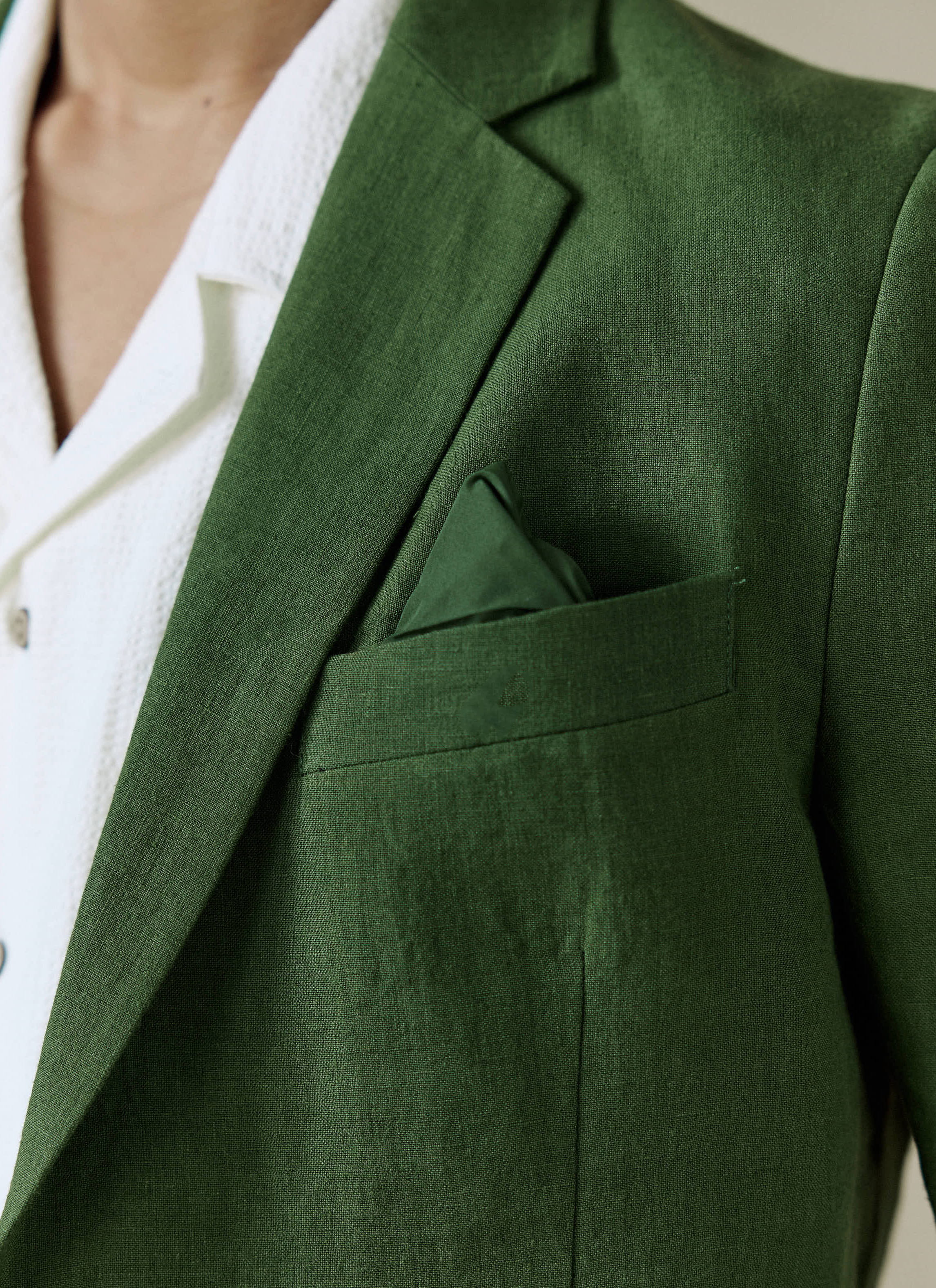 Close up of the Percival forest green tailored linen blazer, featuring a chest pocket and matching pocket square.