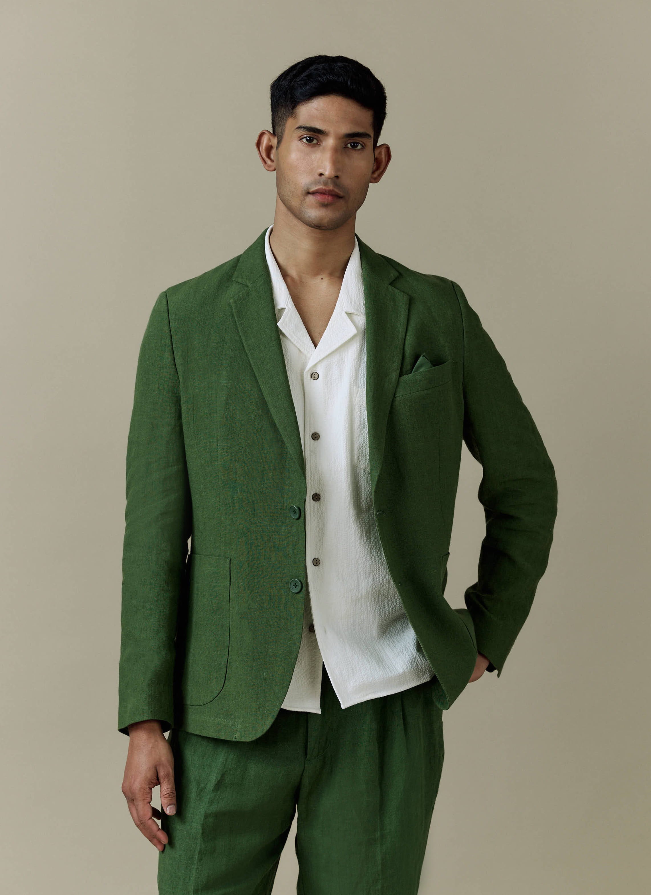 Percival forest green tailored linen blazer styled with matching trousers and a textured white shirt.