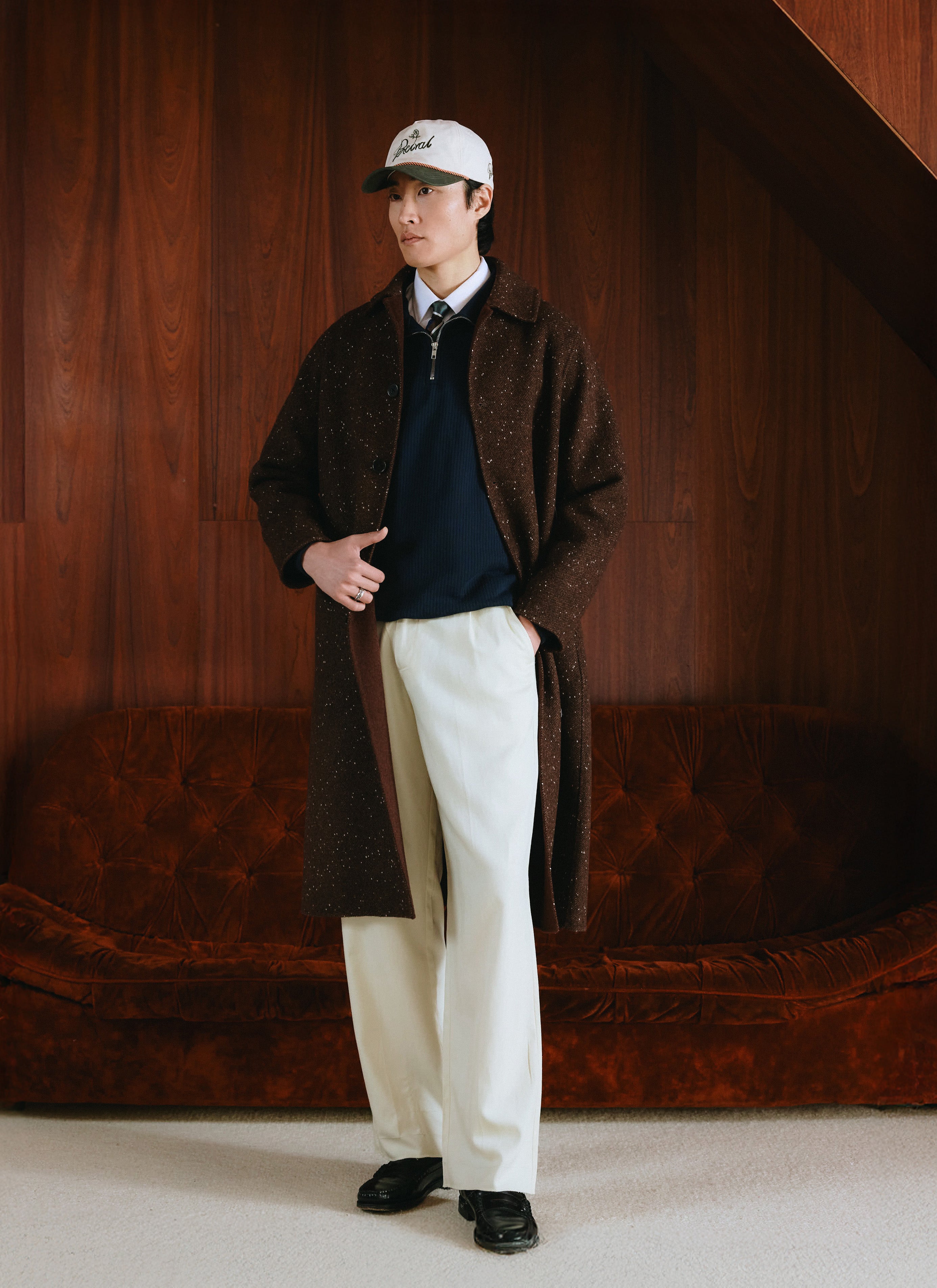 A model wearing the Percival brown fleck double-faced overcoat over a zip-up knit and white trousers.