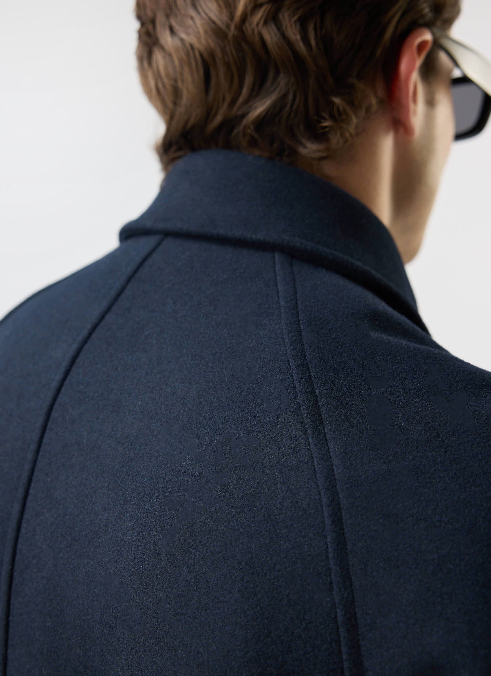 Close-up of the collar and shoulder seam detail on the navy Wool Car Coat from Percival, seen from behind a model.