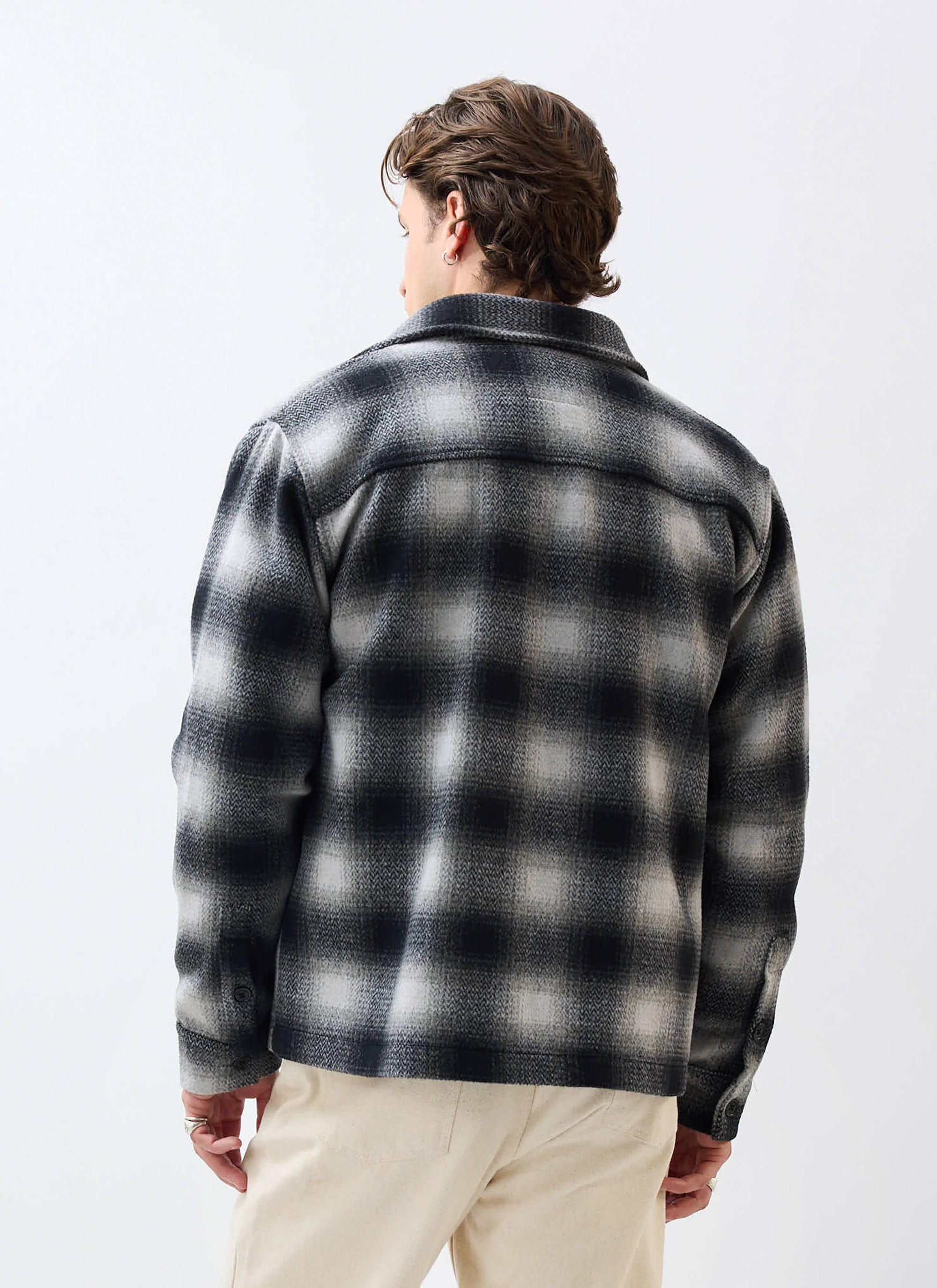 Back view of a model wearing the Percival Check Overshirt in a grey and black wool blend against a white background.