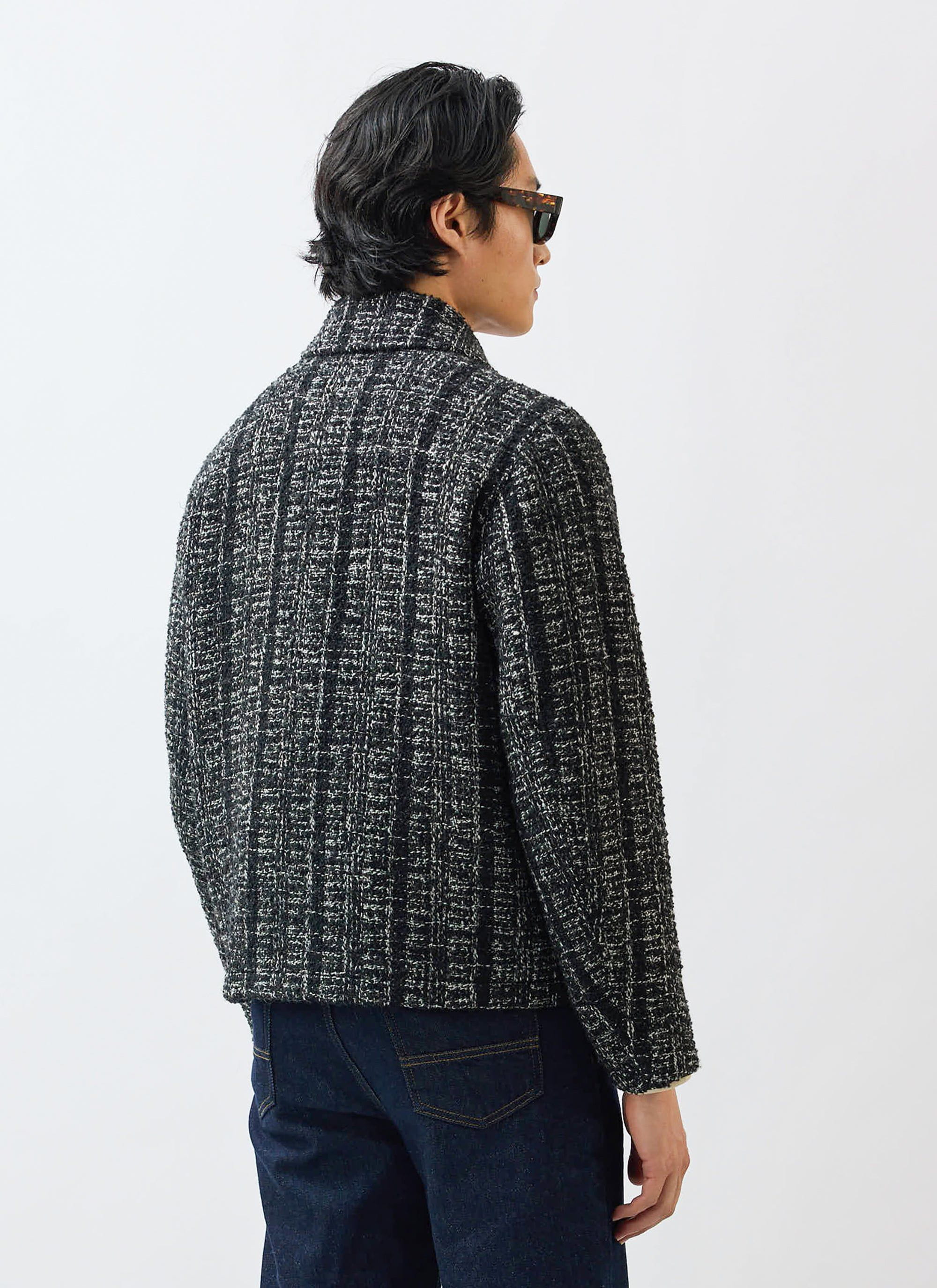 A back view of a model wearing the Percival Ingegno Zip Wool Boxy Jacket in a black and ivory bouclé tweed.