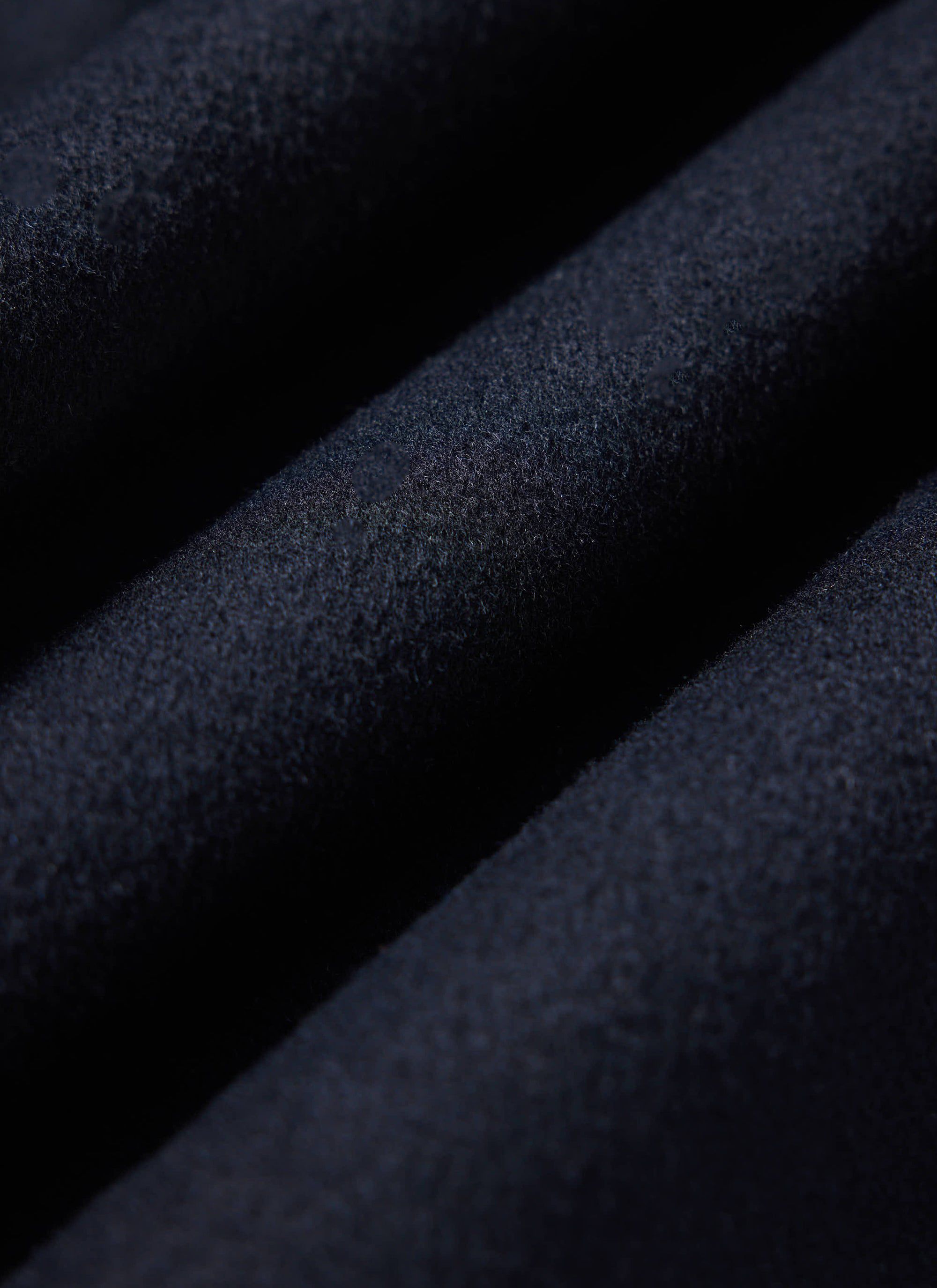 A close-up of the rich navy wool fabric of the Percival Heavy Wool Overshirt, highlighting its soft texture.