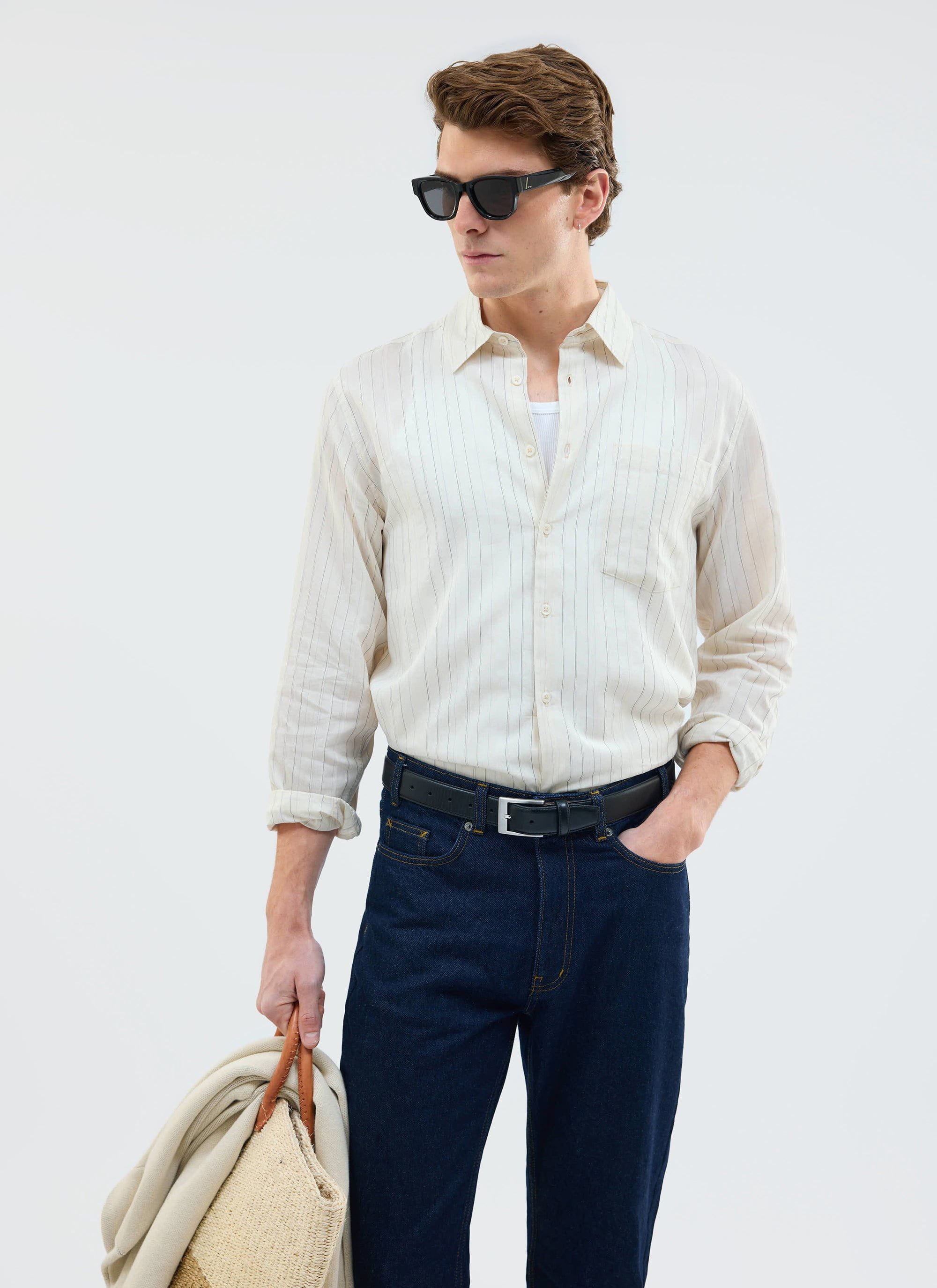 A male model wearing the striped Lorenzo Pearce Shirt in ecru from Percival, styled with dark denim and sunglasses.