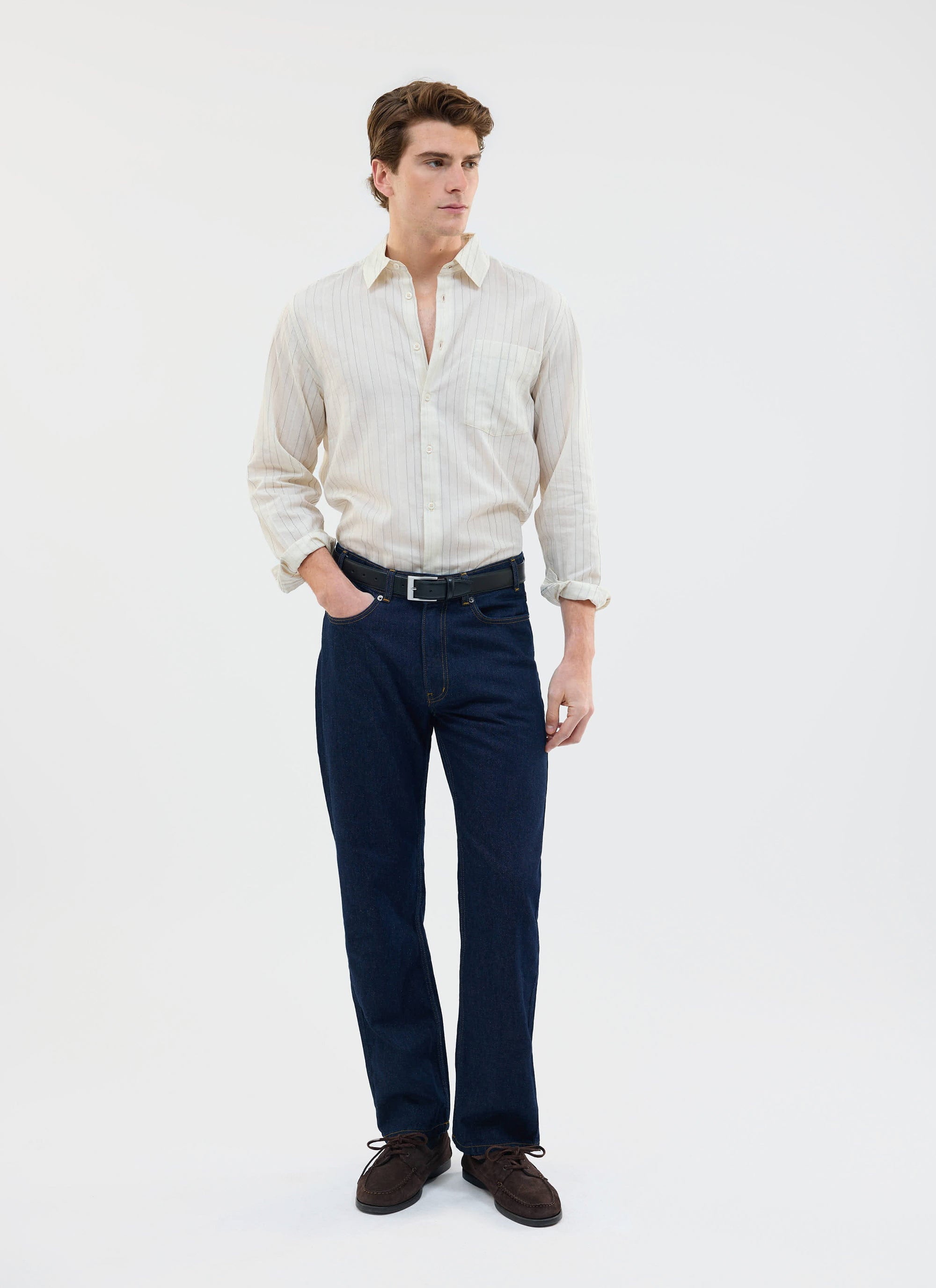 A man models the Percival Lorenzo Pearce Shirt in ecru, a striped long-sleeve style, paired with dark blue jeans.