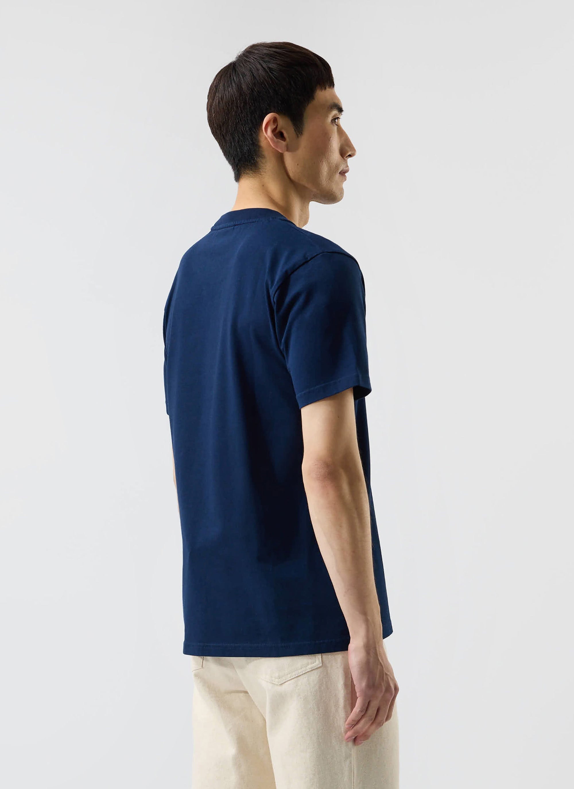 A male model, seen from behind, wears the navy blue Mojito T Shirt from Percival, showing its regular fit.