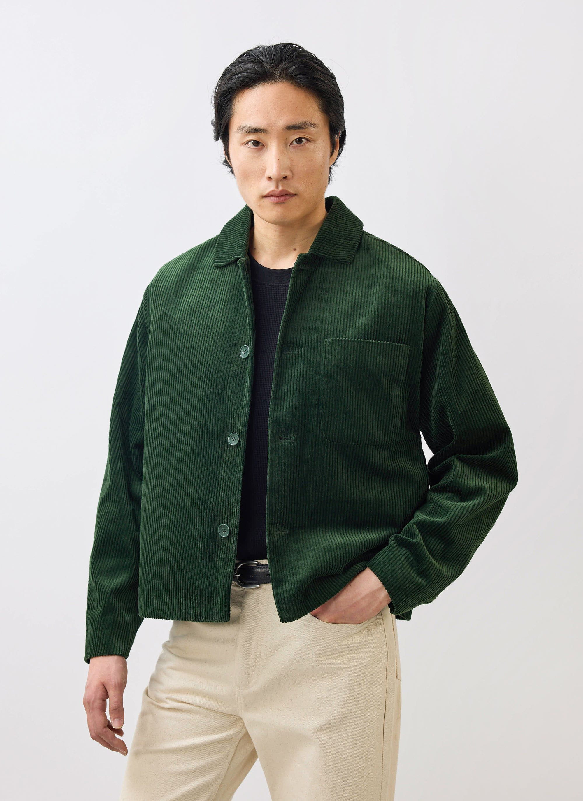 A man models the Percival Cord Overshirt in forest green, styled over a black top with light-coloured trousers.