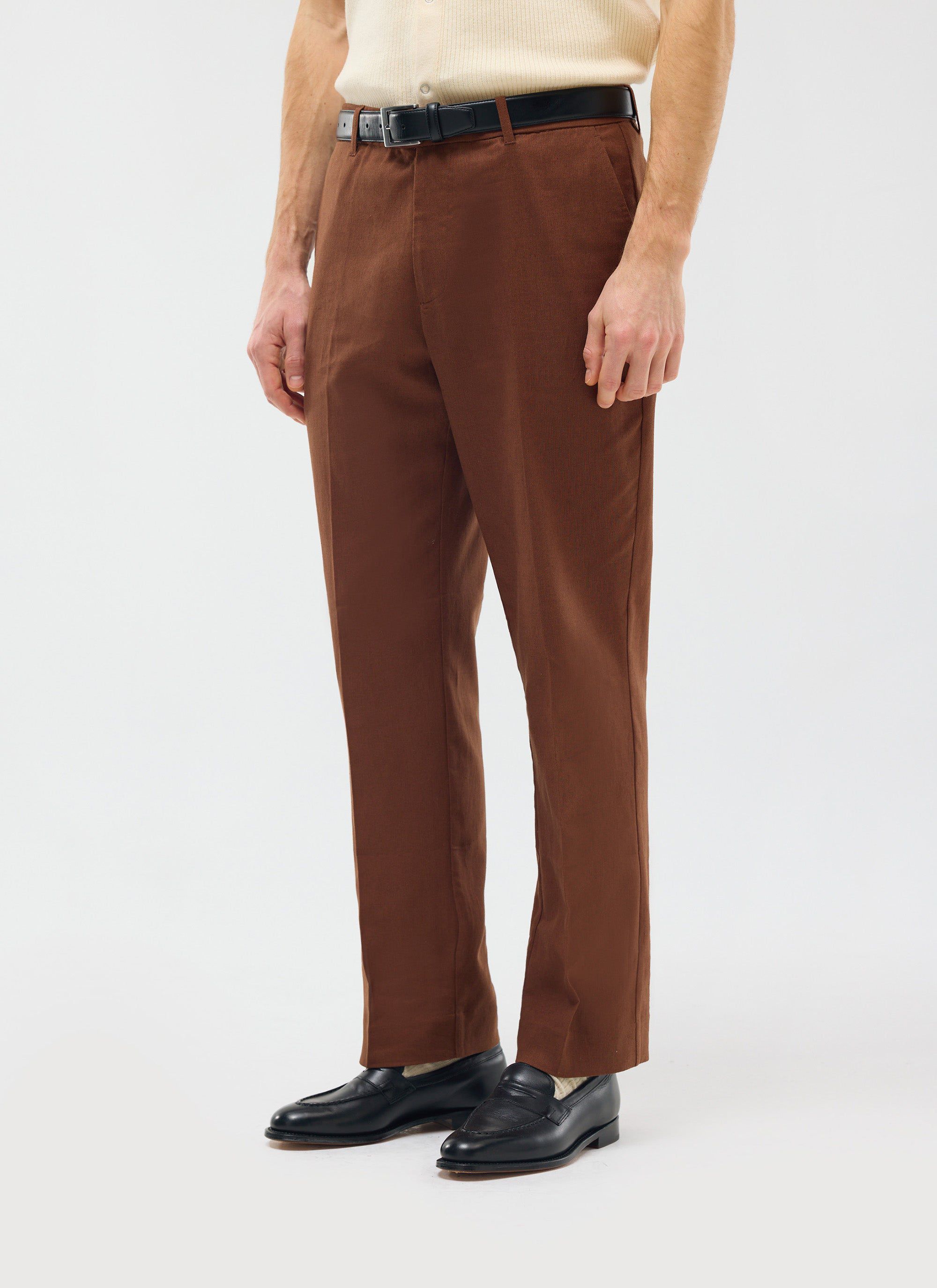 The Percival Tailored Linen Trousers in brown, worn by a model with a black belt and loafers to show the straight leg fit.