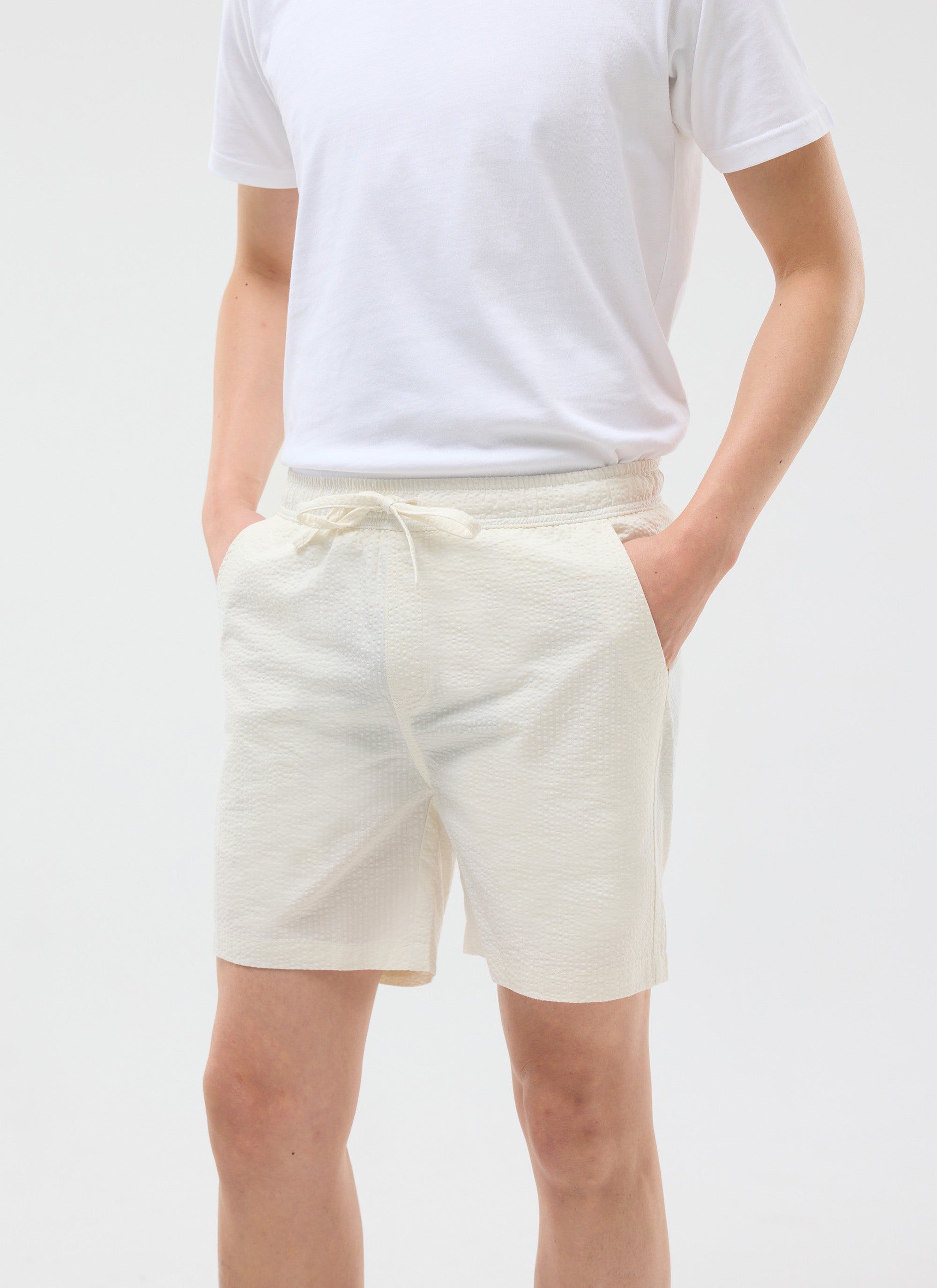 A model wears the cream Percival Classic Shorts in a seersucker fabric, styled with a simple white t-shirt.