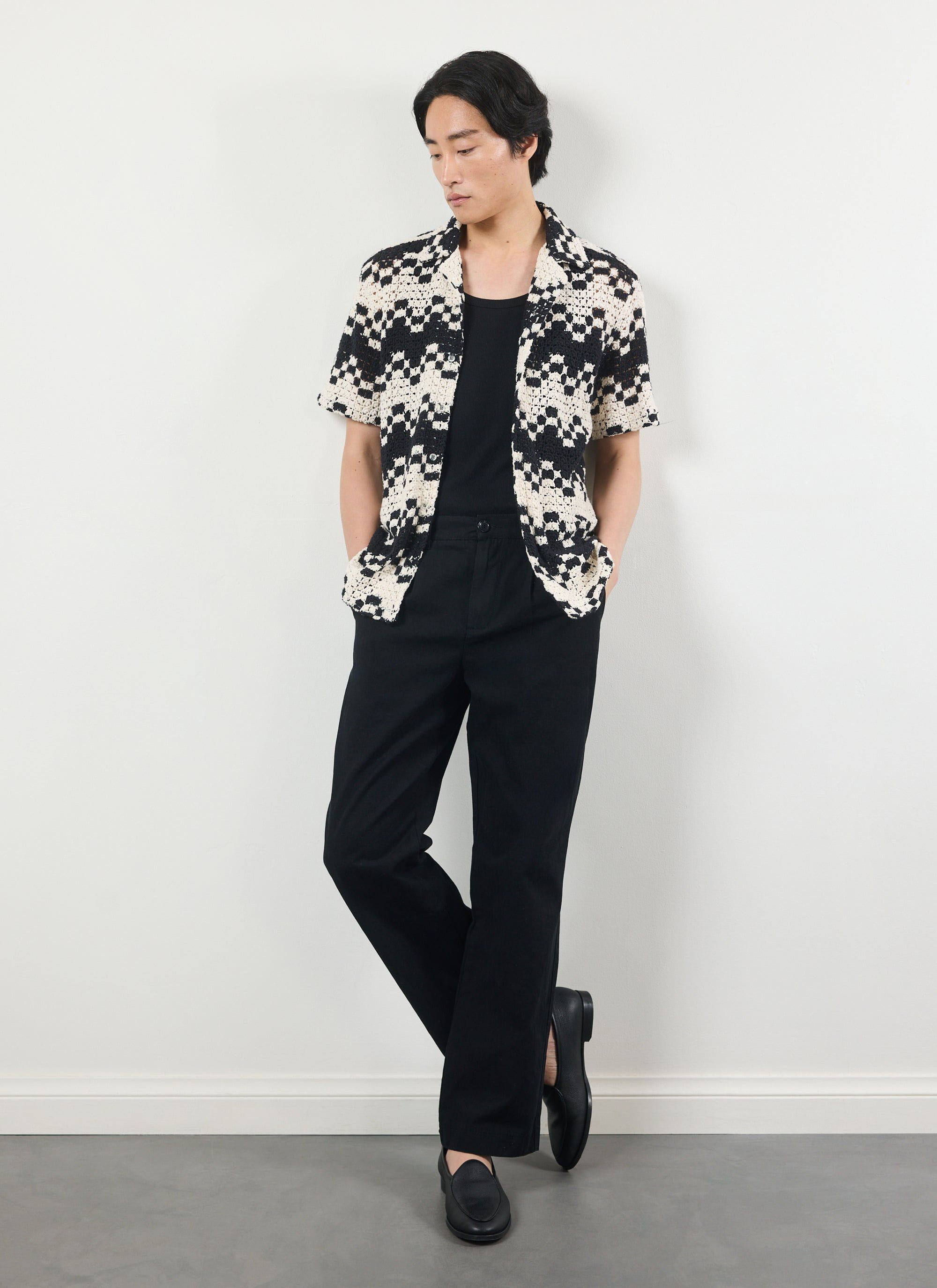A model wears the Percival Naples Crochet Cuban Shirt in ecru, styled open over a black top and trousers.