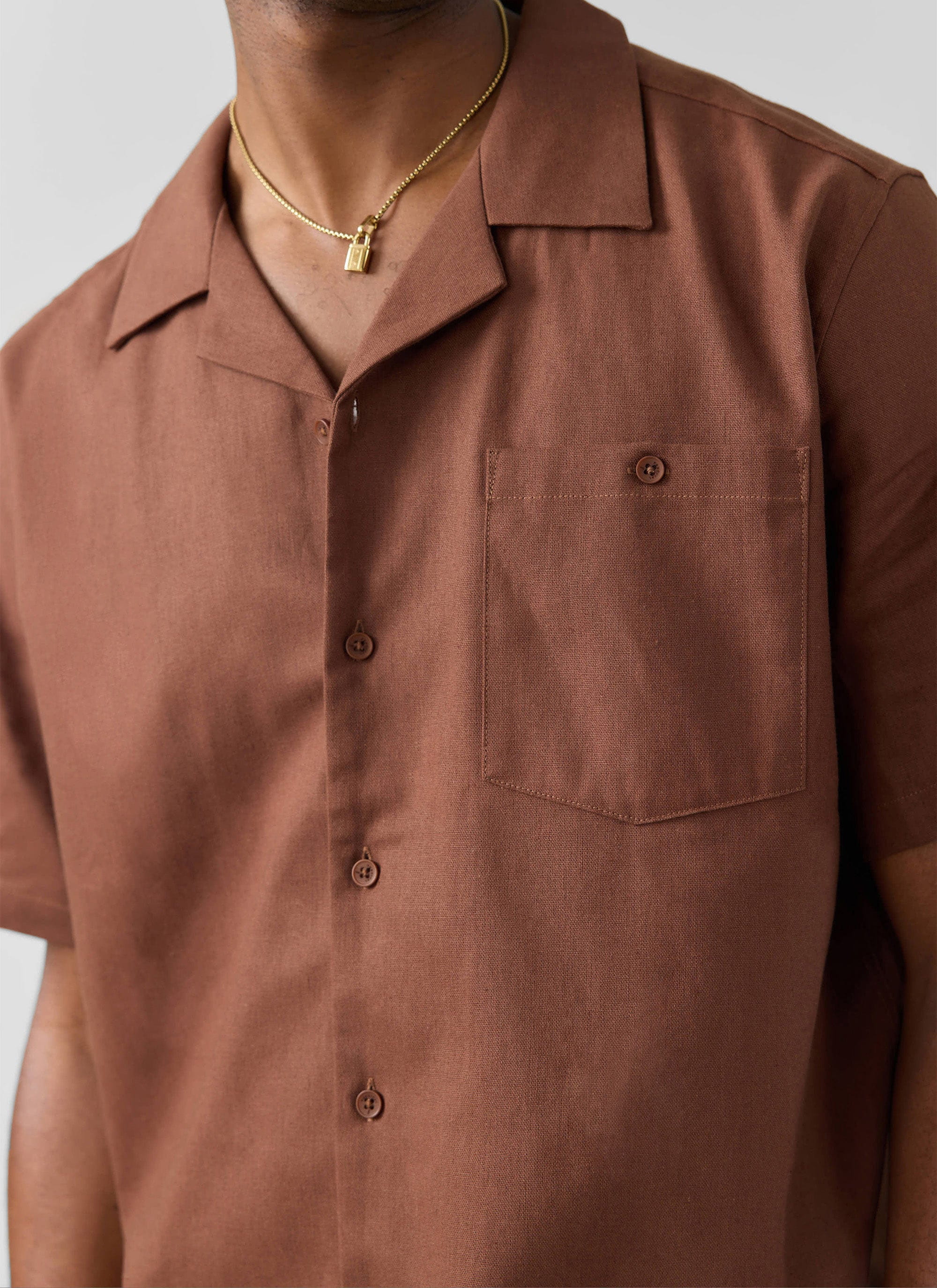 Close-up on a model wearing the Percival Short Sleeve Cuban Shirt in brown linen, showing the Cuban collar and chest pocket.