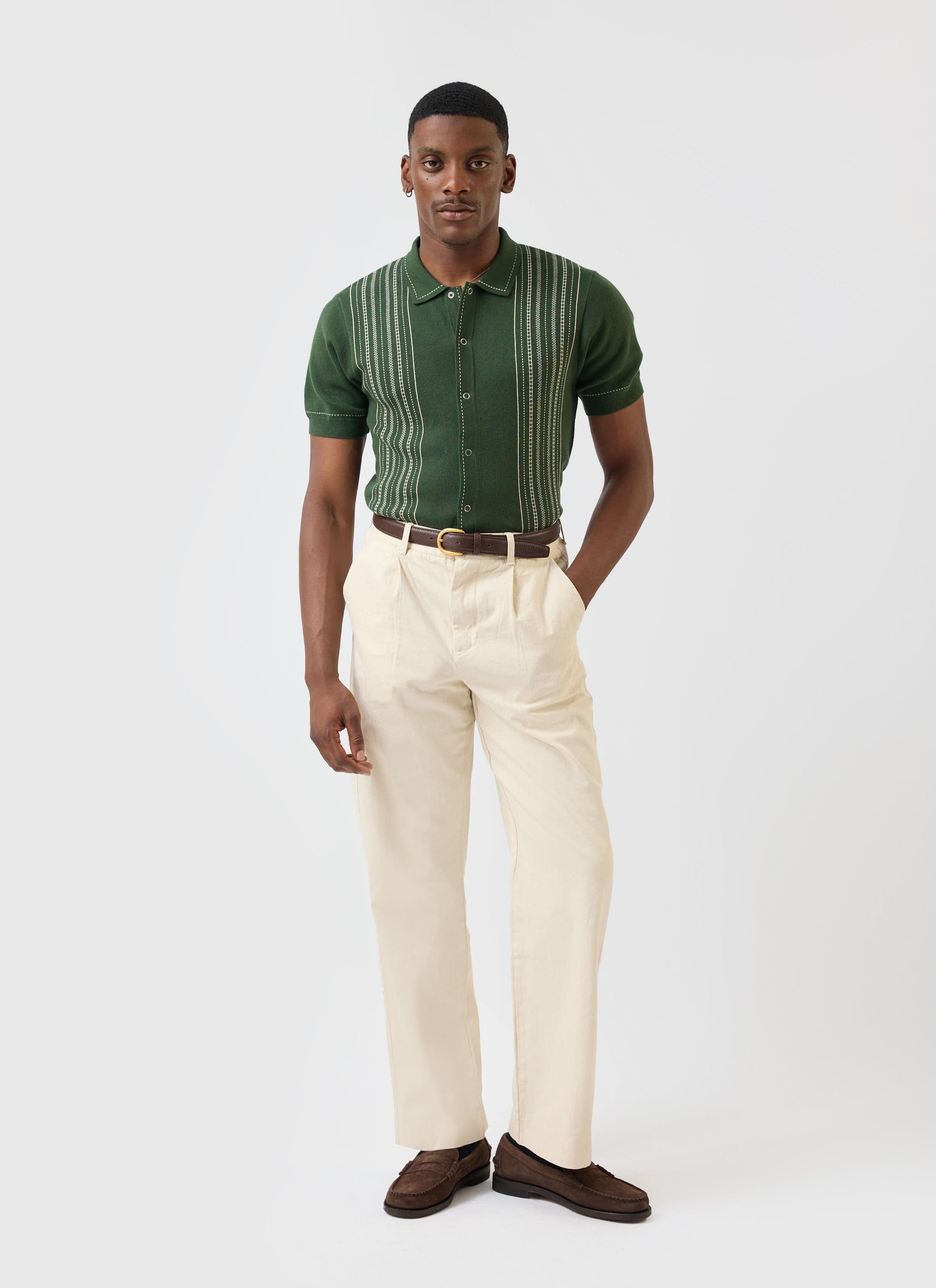 A model wears the Percival Accolades Knitted Shirt in forest green, styled with cream trousers and brown loafers.