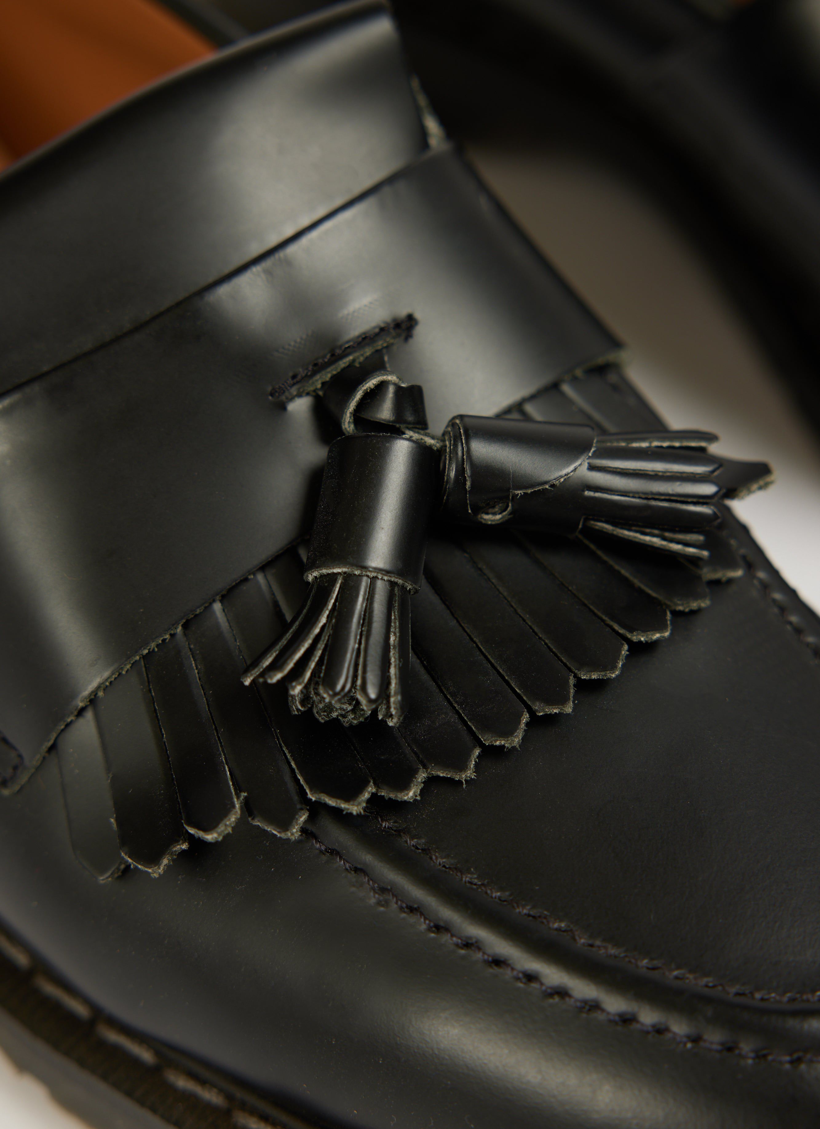 Close up of Percival's black hi-shine leather tassel loafer with fringe detail.